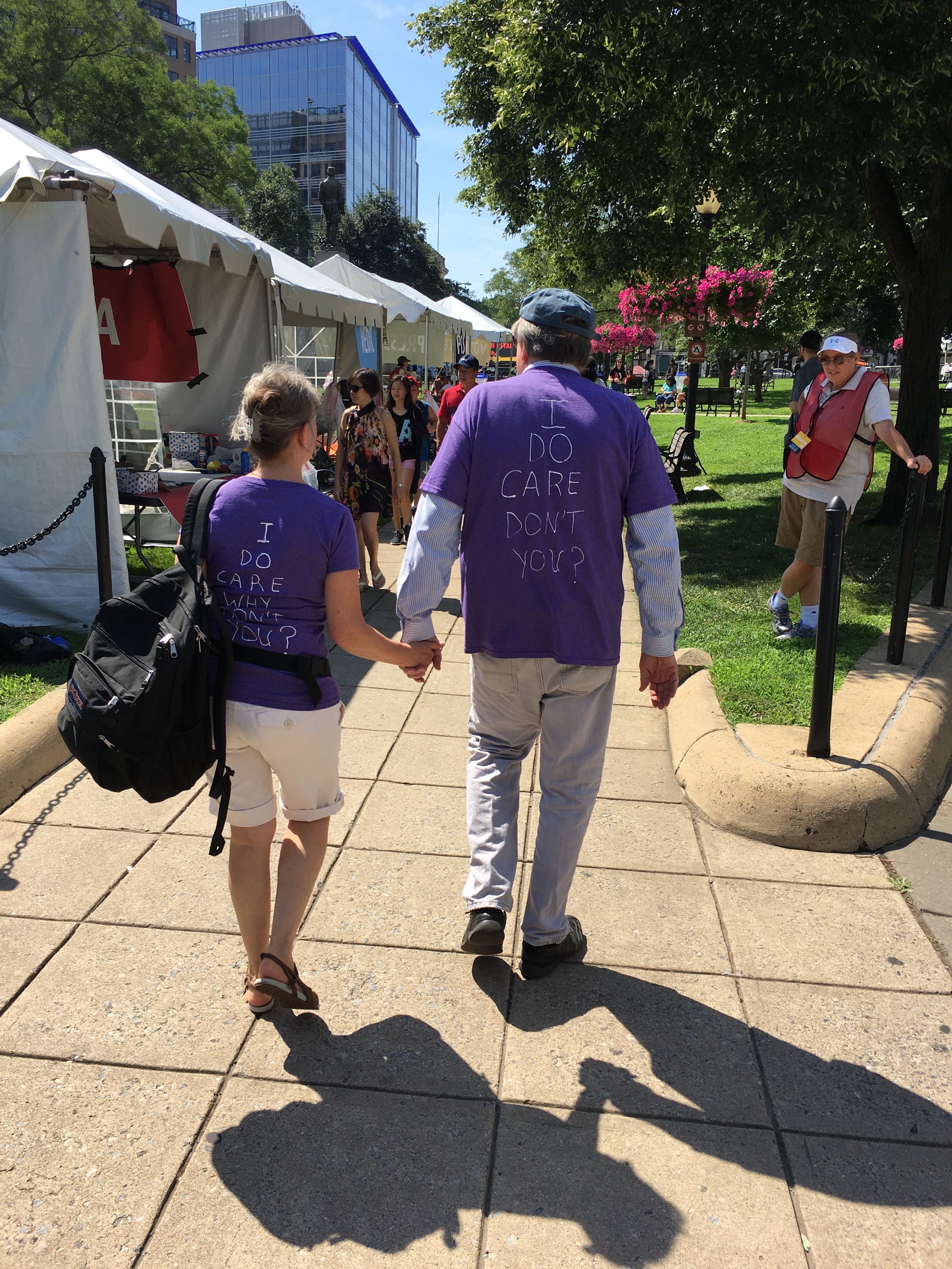 A couple holds hands wearing shirts that say, "I do care, don't you?"