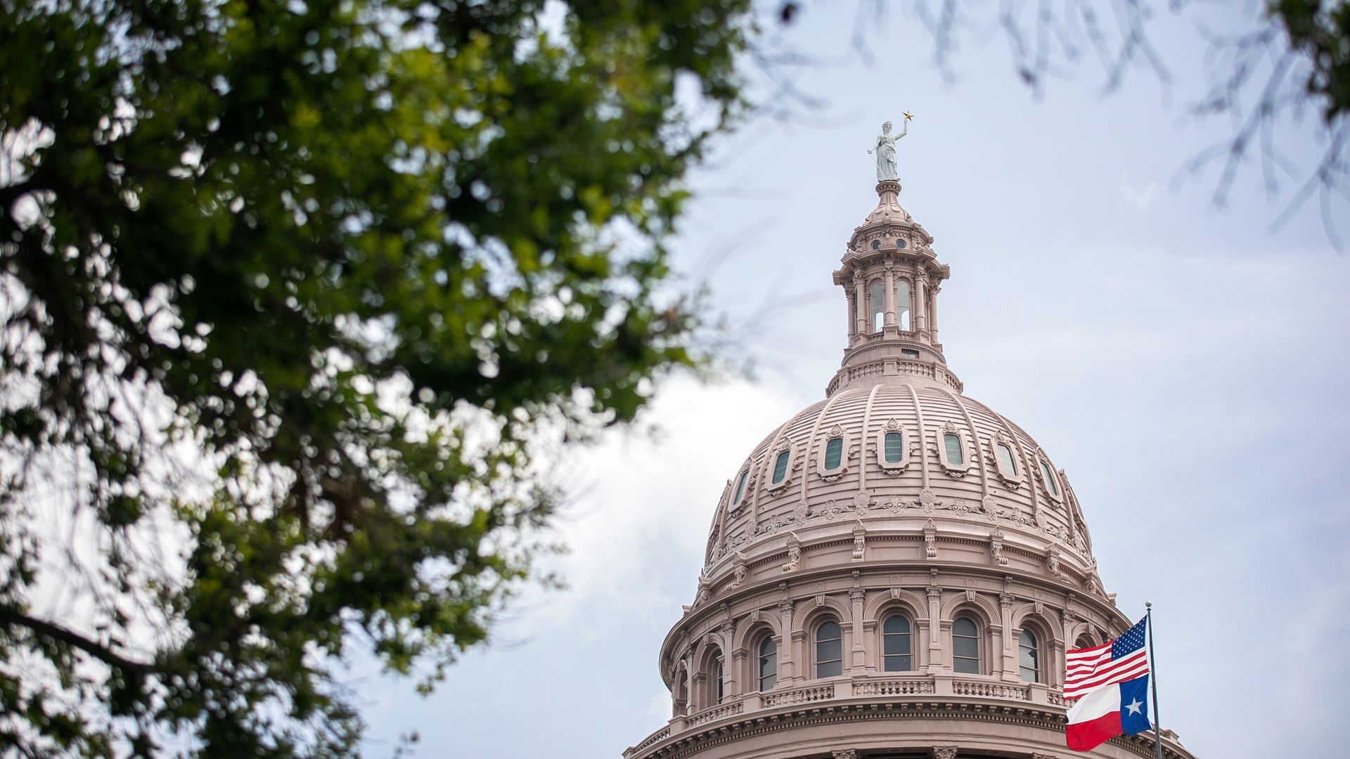 The U.S. and Texas flags wave outside the Texas State Capitol in Austin.