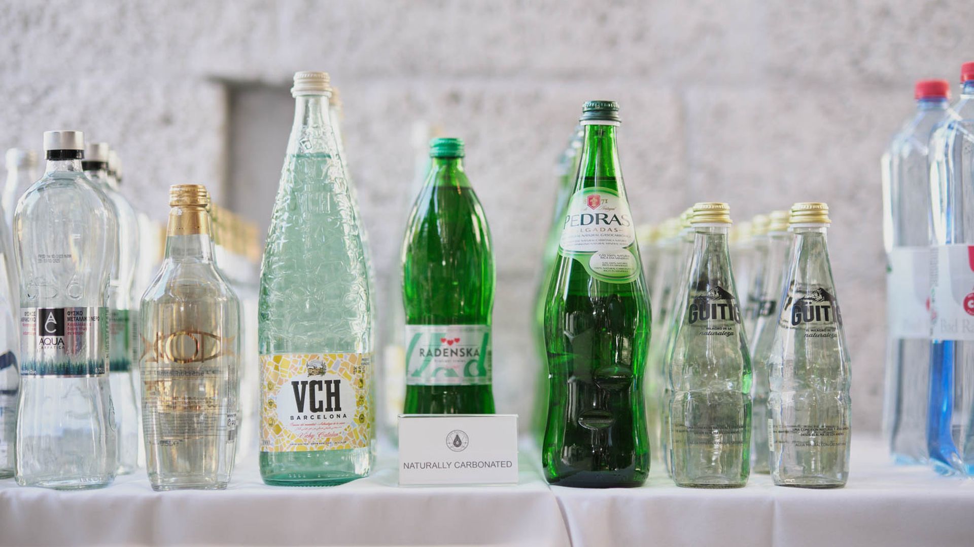 Bottles of fine water lined up on a table.