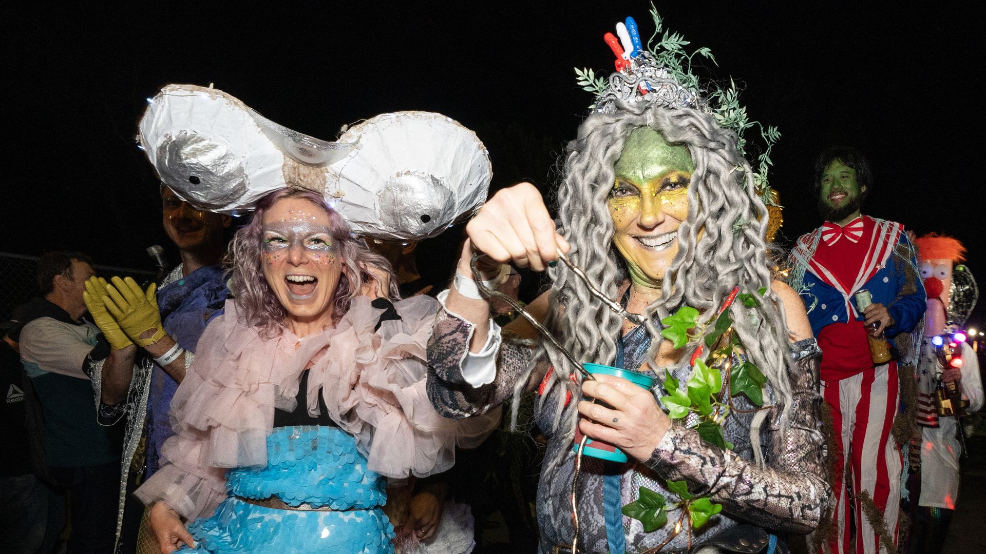Two parade marchers, dressed in outlandish costumes, smile for the camera.