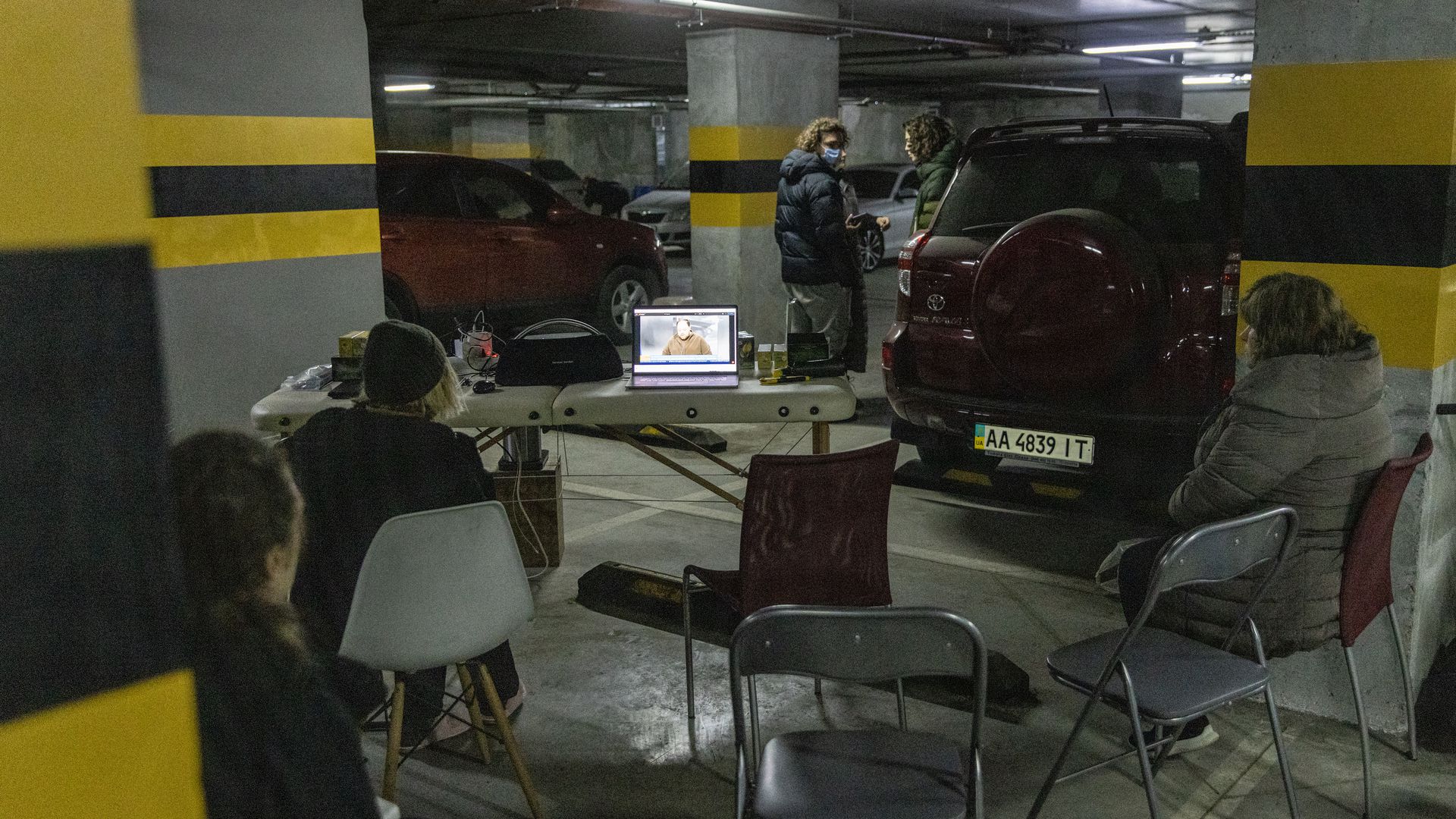 Residents watch the news on a laptop in the carpark of a large apartment block that they are using as a bomb shelter on March 01, 2022 in Kyiv, Ukraine.