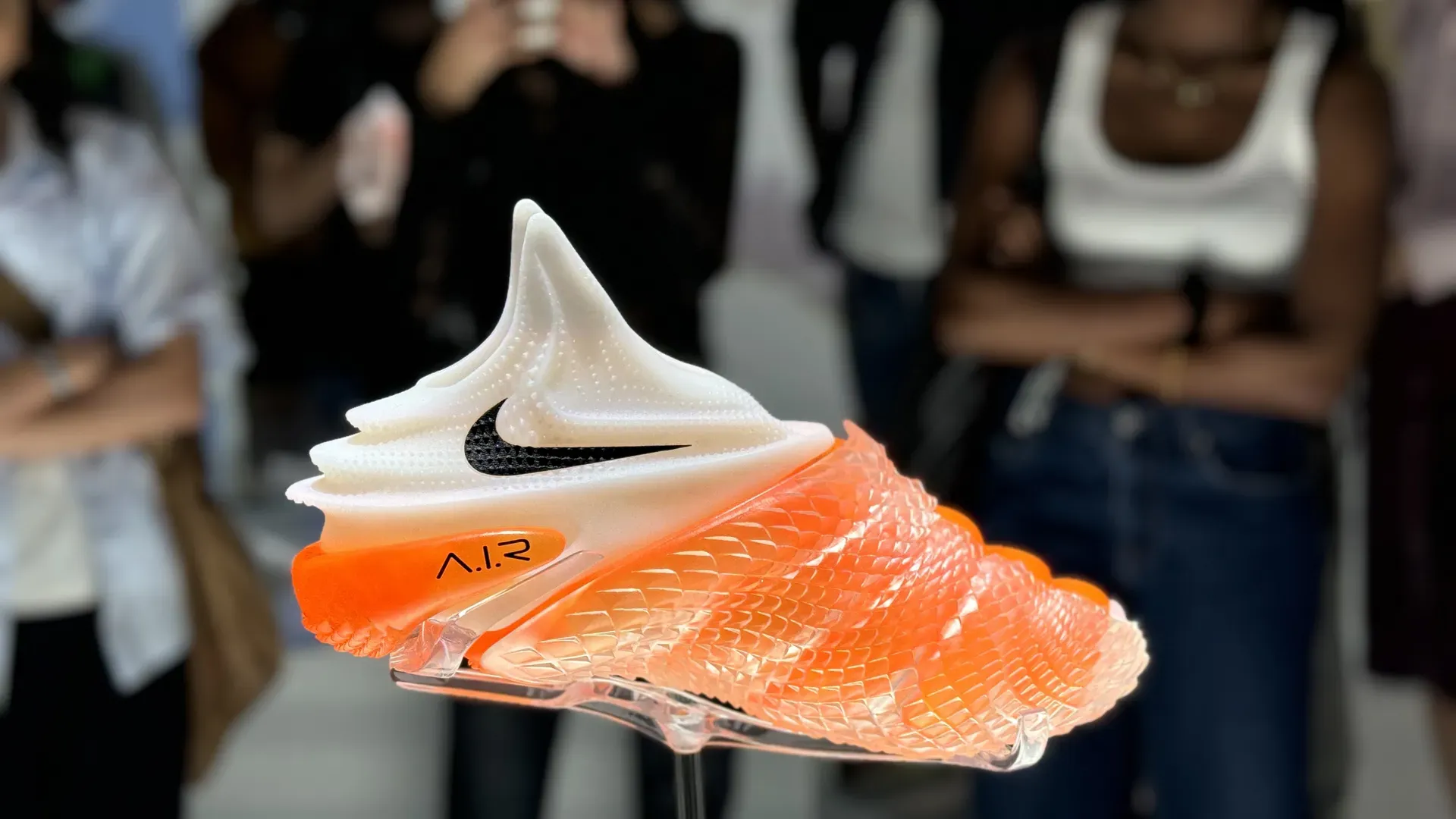 An orange Nike Air shoe designed with AI on display in Paris as part of the Art of Victory exhibit.