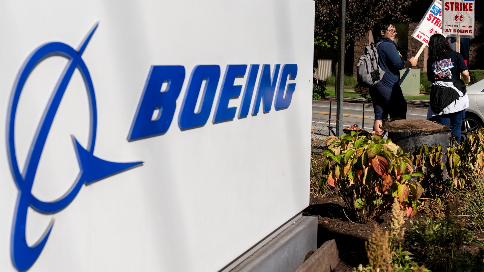 Workers picket alongside a corporate sign for Boeing