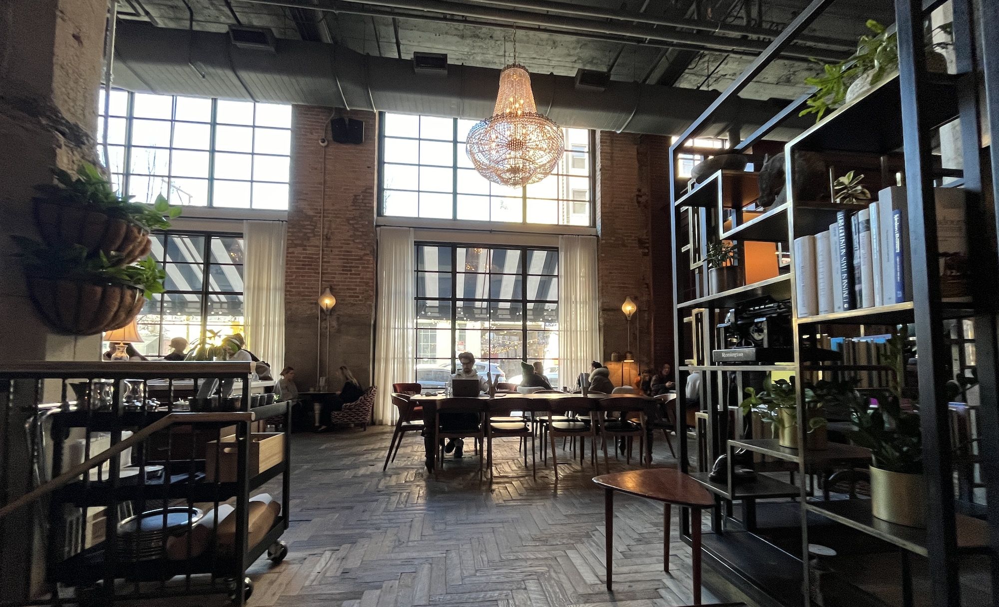 interior of restaurant with large glass chandelier, tables and bookshelves.