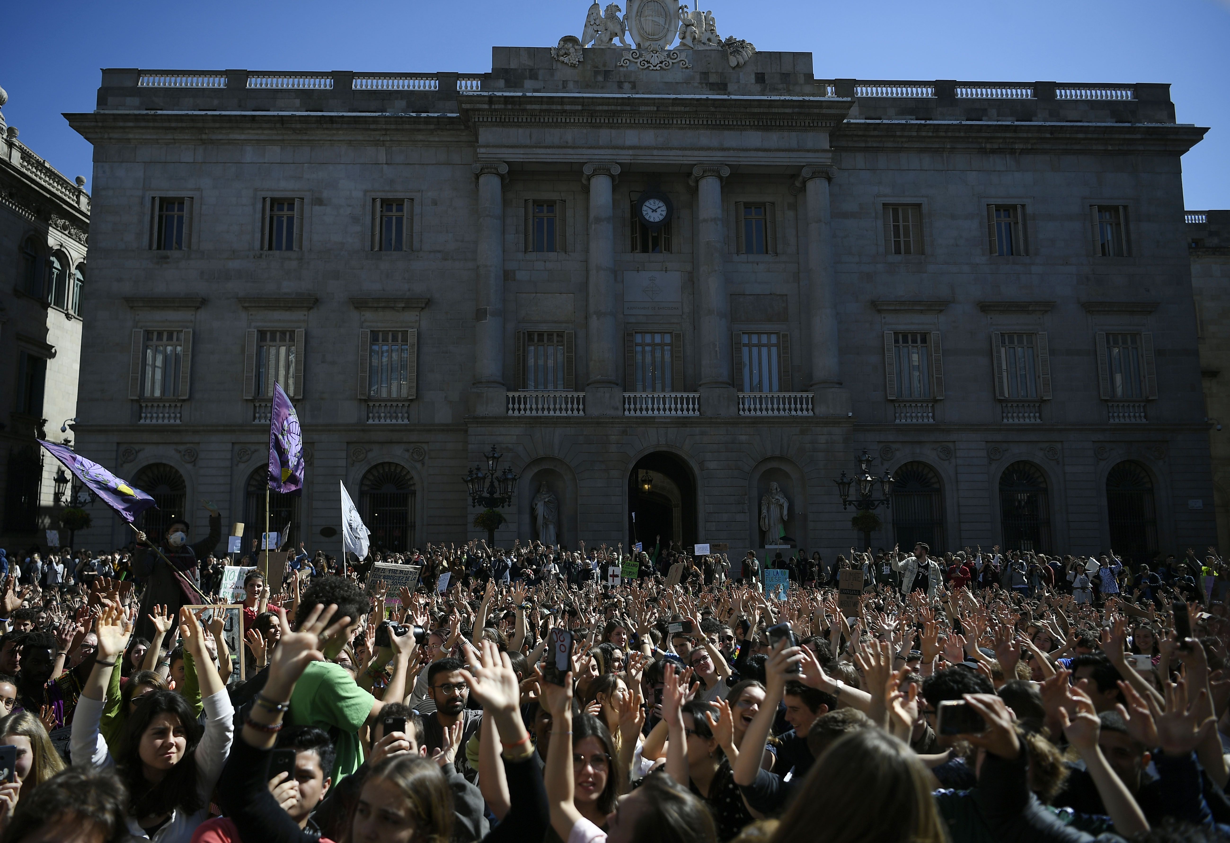 A large sea of student protestors stand in front of a grand building in Madrid.