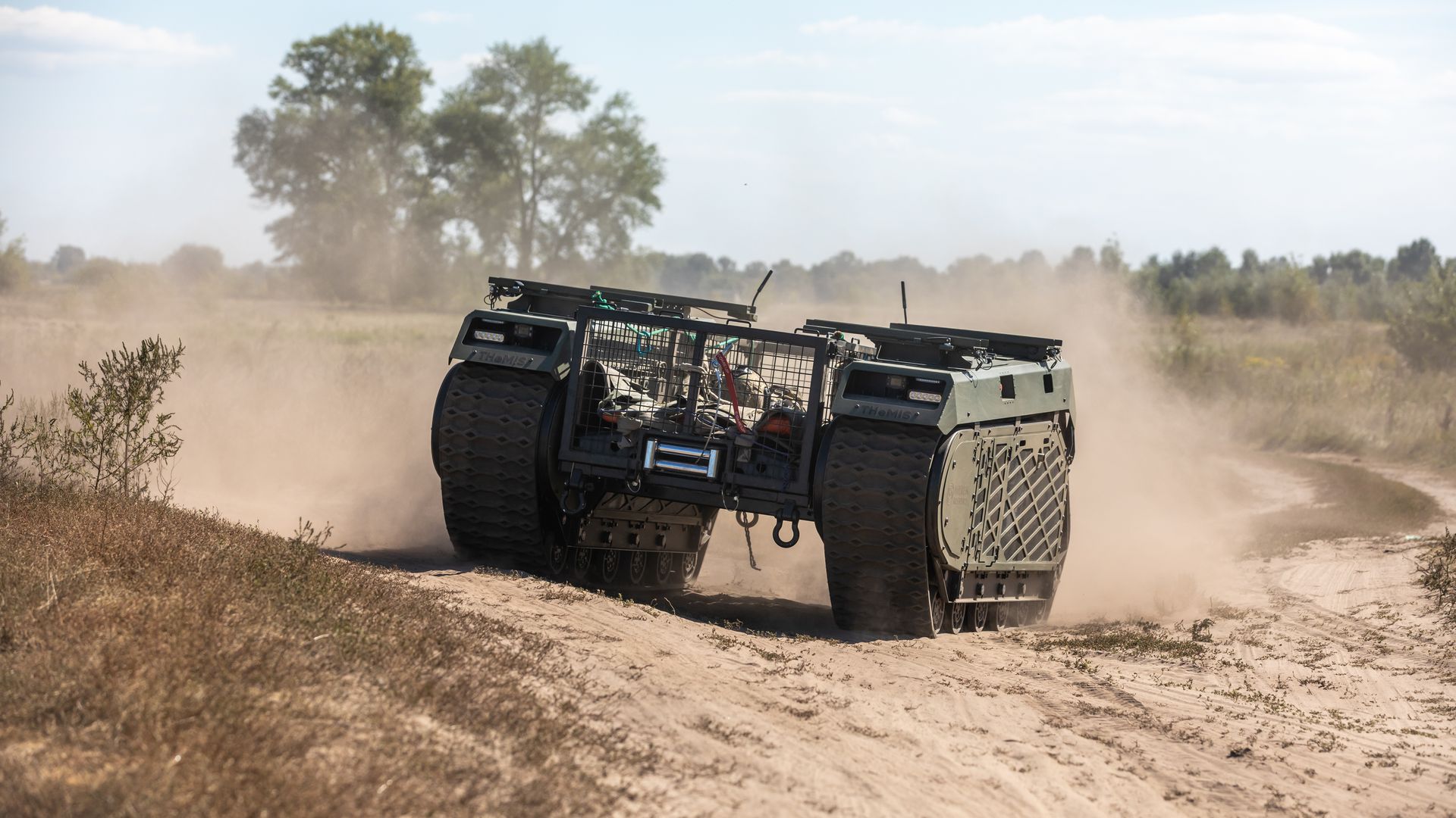 A THeMIS multi-purpose tracked unmanned ground vehicle is seen on a dusty road while carrying a wounded fighter during the field tests.