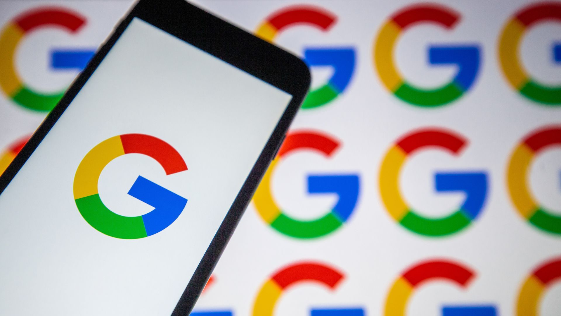 A photo of a smartphone with a Google logo against a background of Google logos