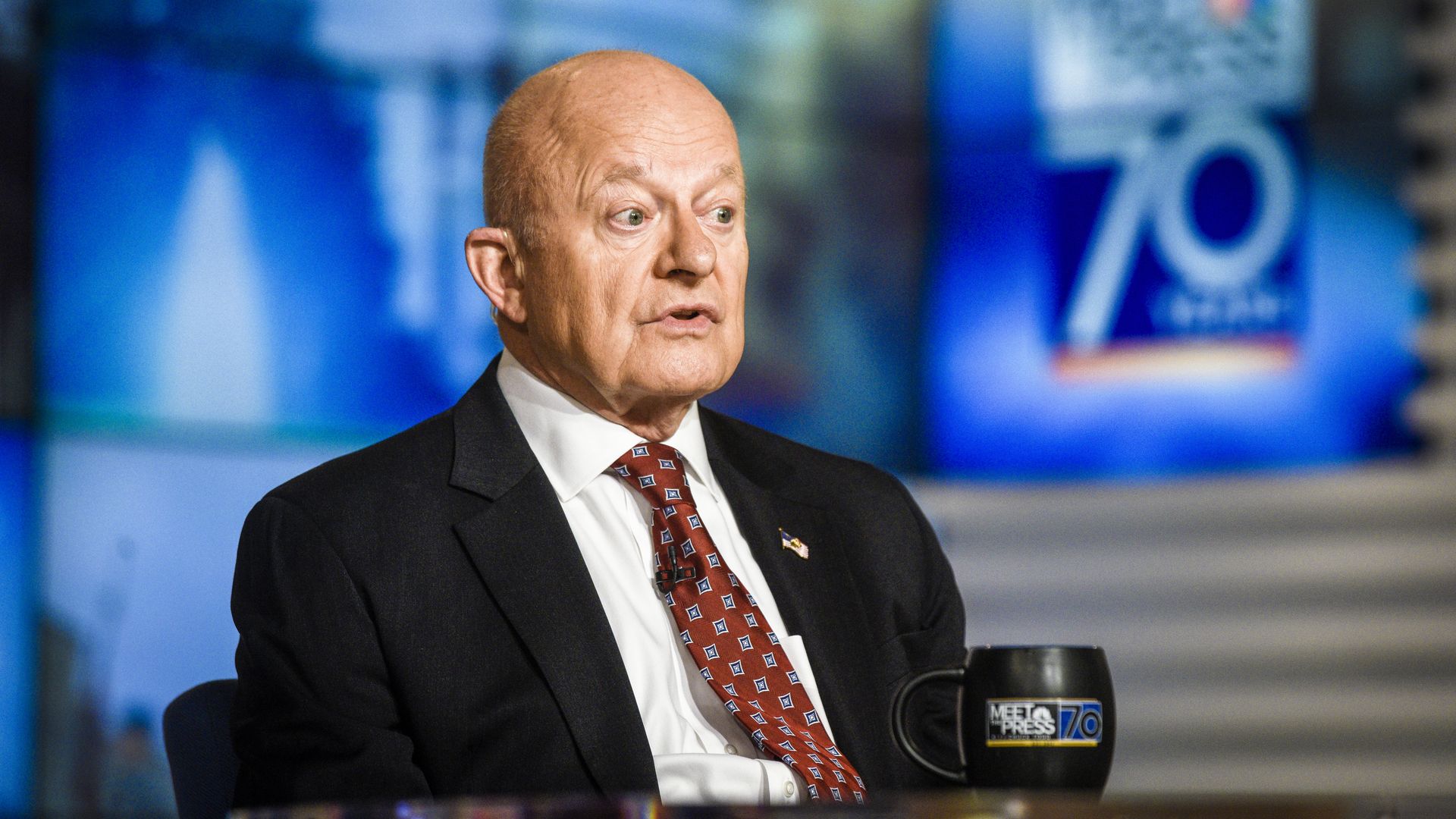 James Clapper sitting at a desk on a TV set with his eyes wide open