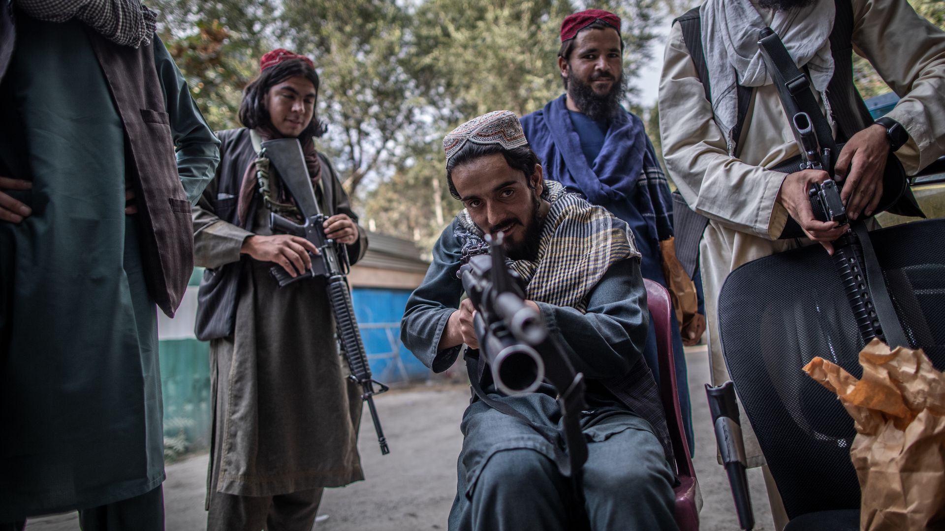 A young Taliban fighter aims his rifle in the direction of a photographer for fun as he stands guard outside a police station in Kabul. 