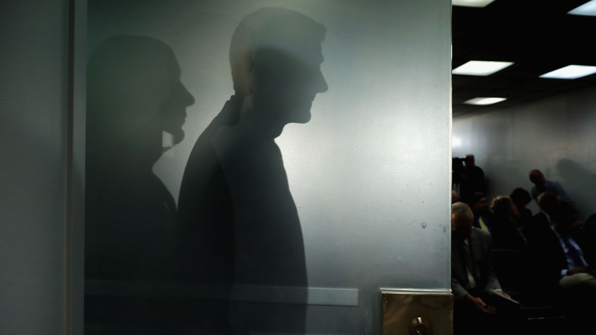 House Speaker Paul Ryan casts his shadow on a glass door.