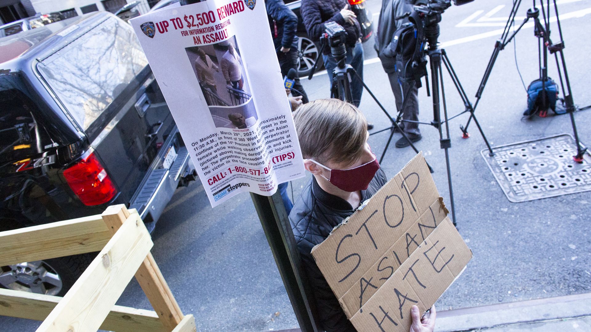 A picture of a person holding a sign that says stop asian hate next to a wanted poster.