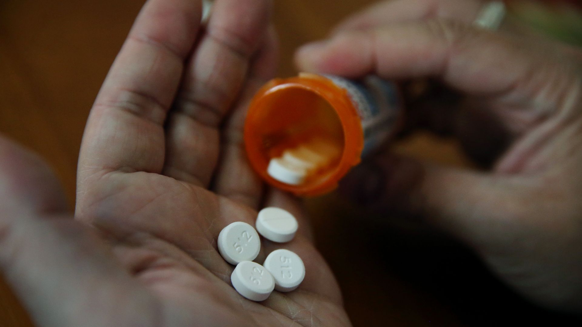 A patient pours prescription bills out of a bottle into his hand.