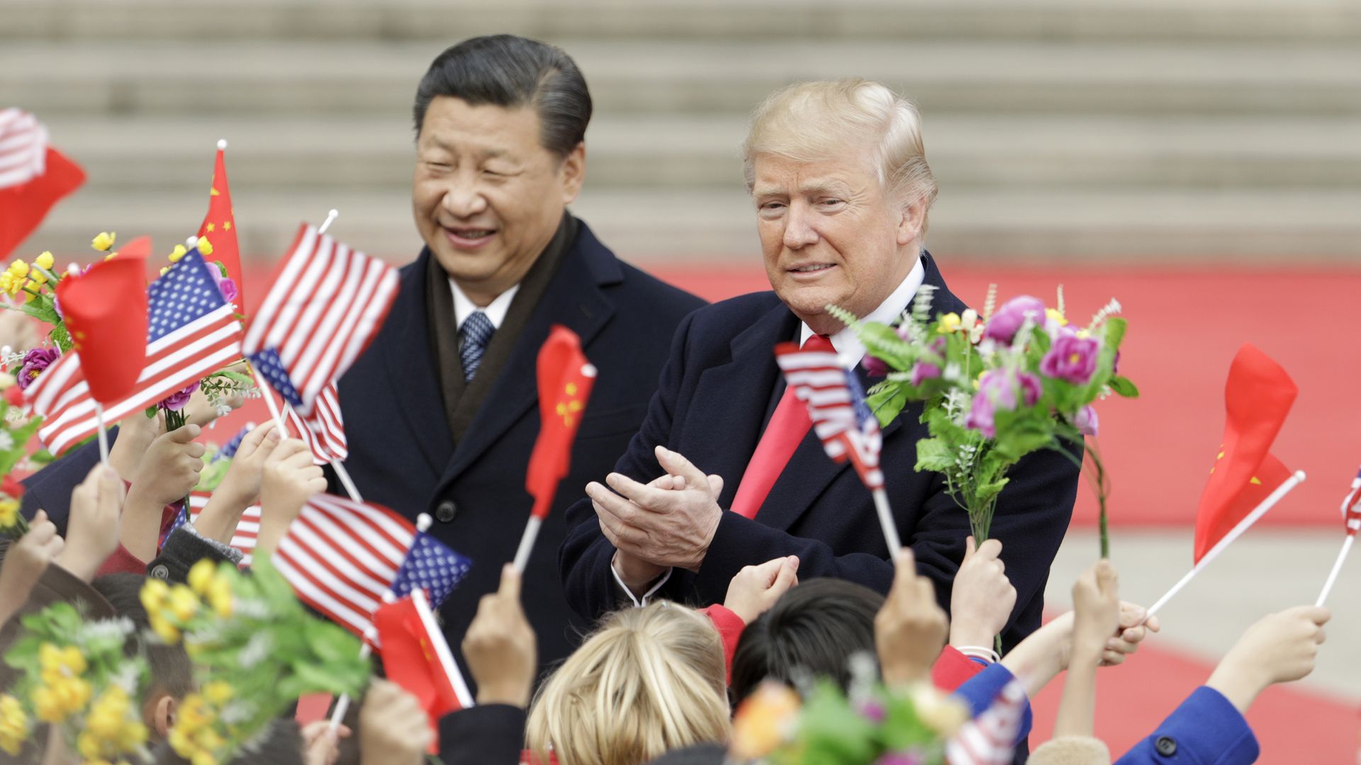 Trump and Xi with people waving American and Chinese flags.