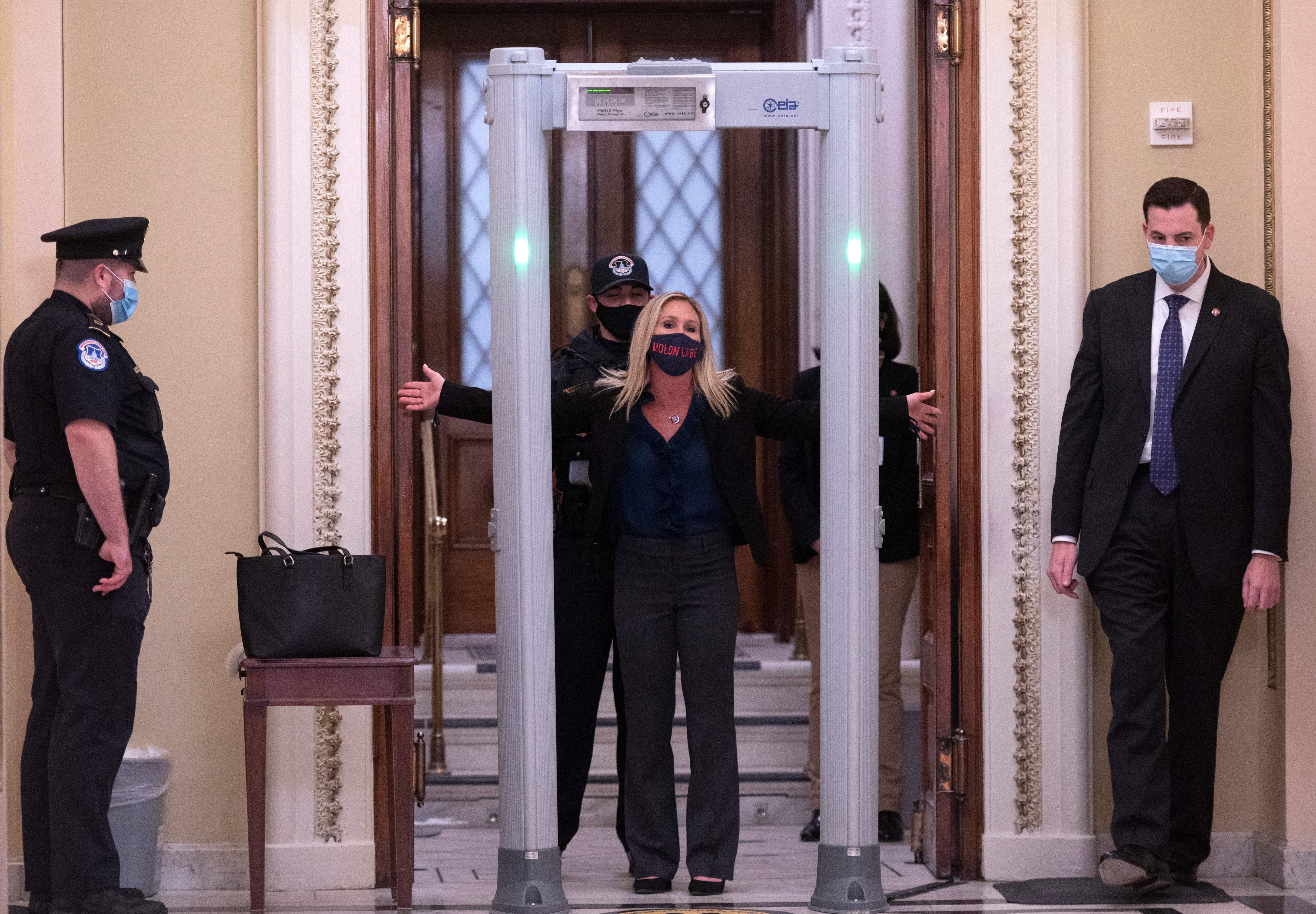 Picture of Representative Marjorie Taylor Greene (R-GA) spreads out her arms as she goes through security outside the House Chamber.