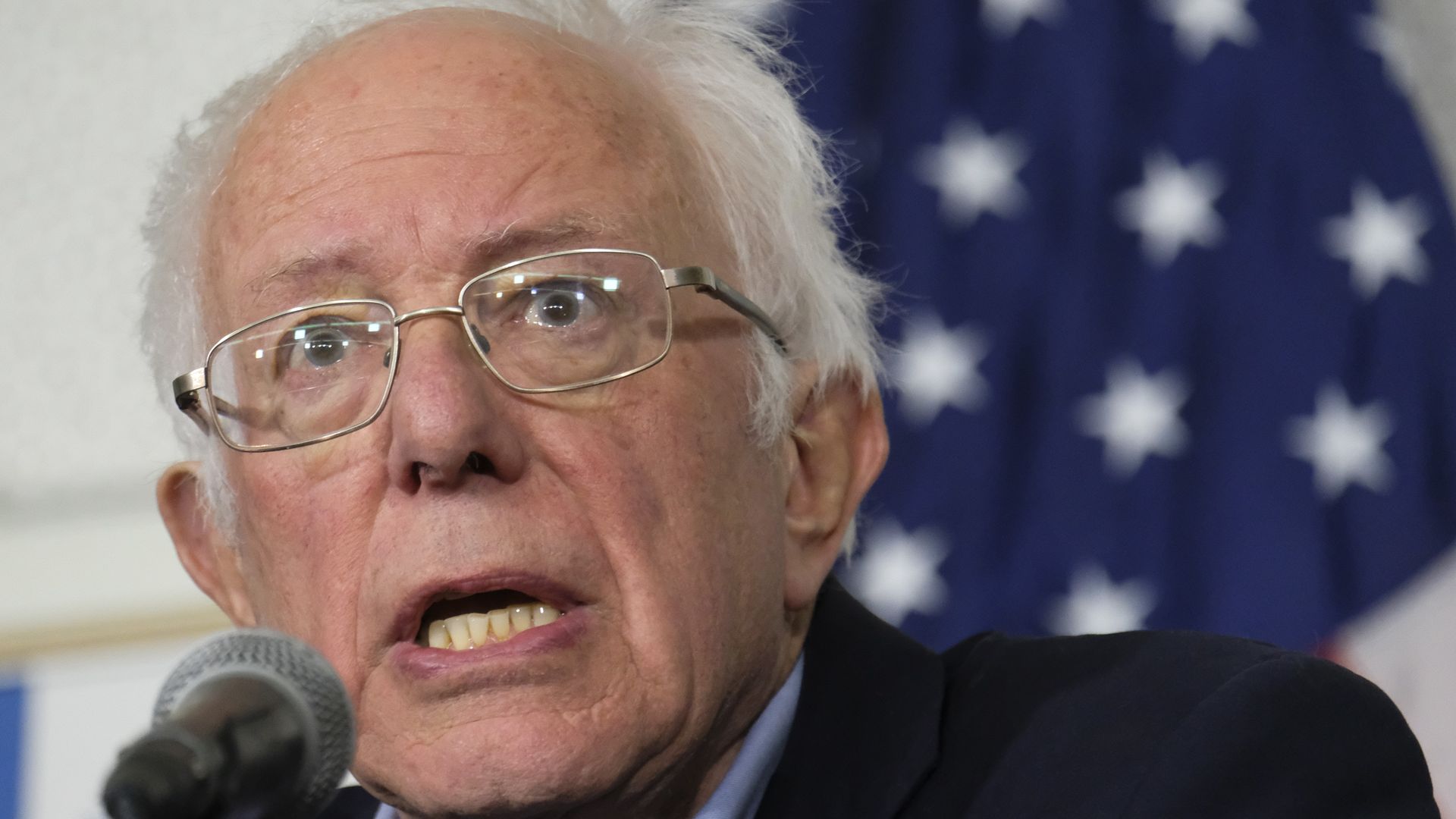 In this image, Bernie Sanders speaks into a microphone.