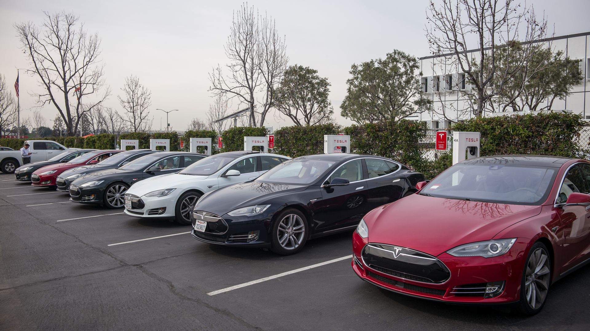 Cars charge at stations outside of Tesla's factory in Fremont
