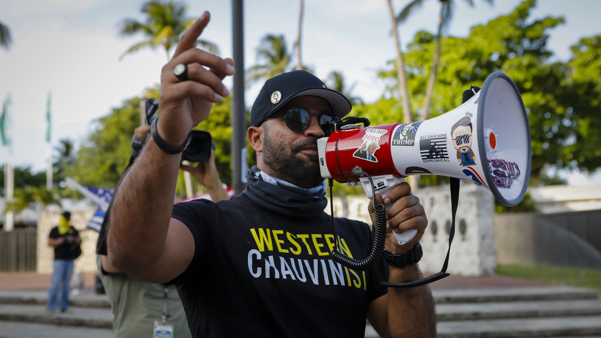 Photo of Enrique Tarrio wearing a shirt that says "Western chauvinism" and speaking into a speakerphone