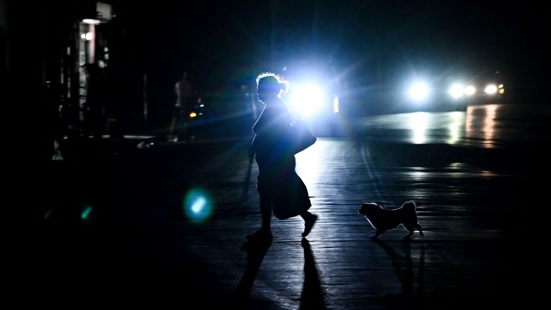 A woman and a dog cross a dark street during a blackout in Havana on March 4, 2026. 
