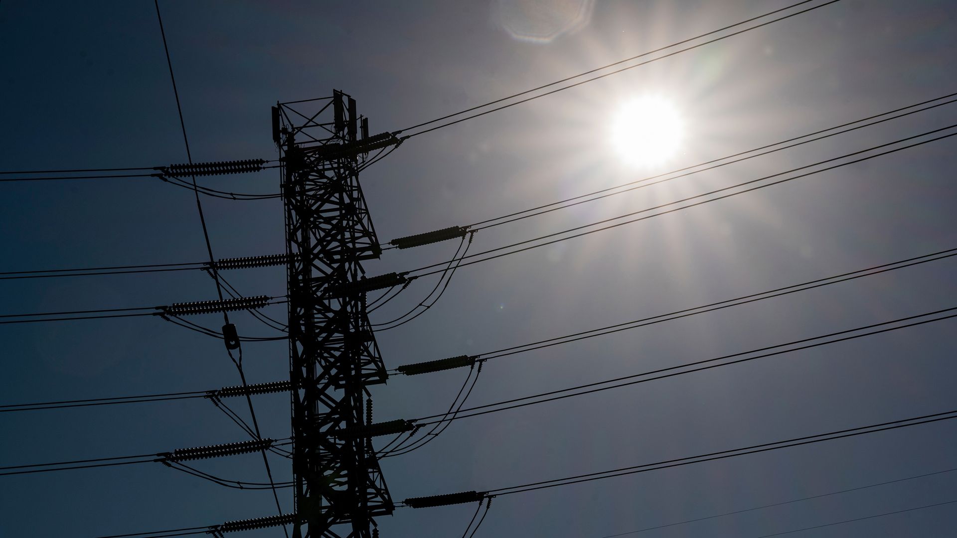 Photo of the sun shining through power lines in California.