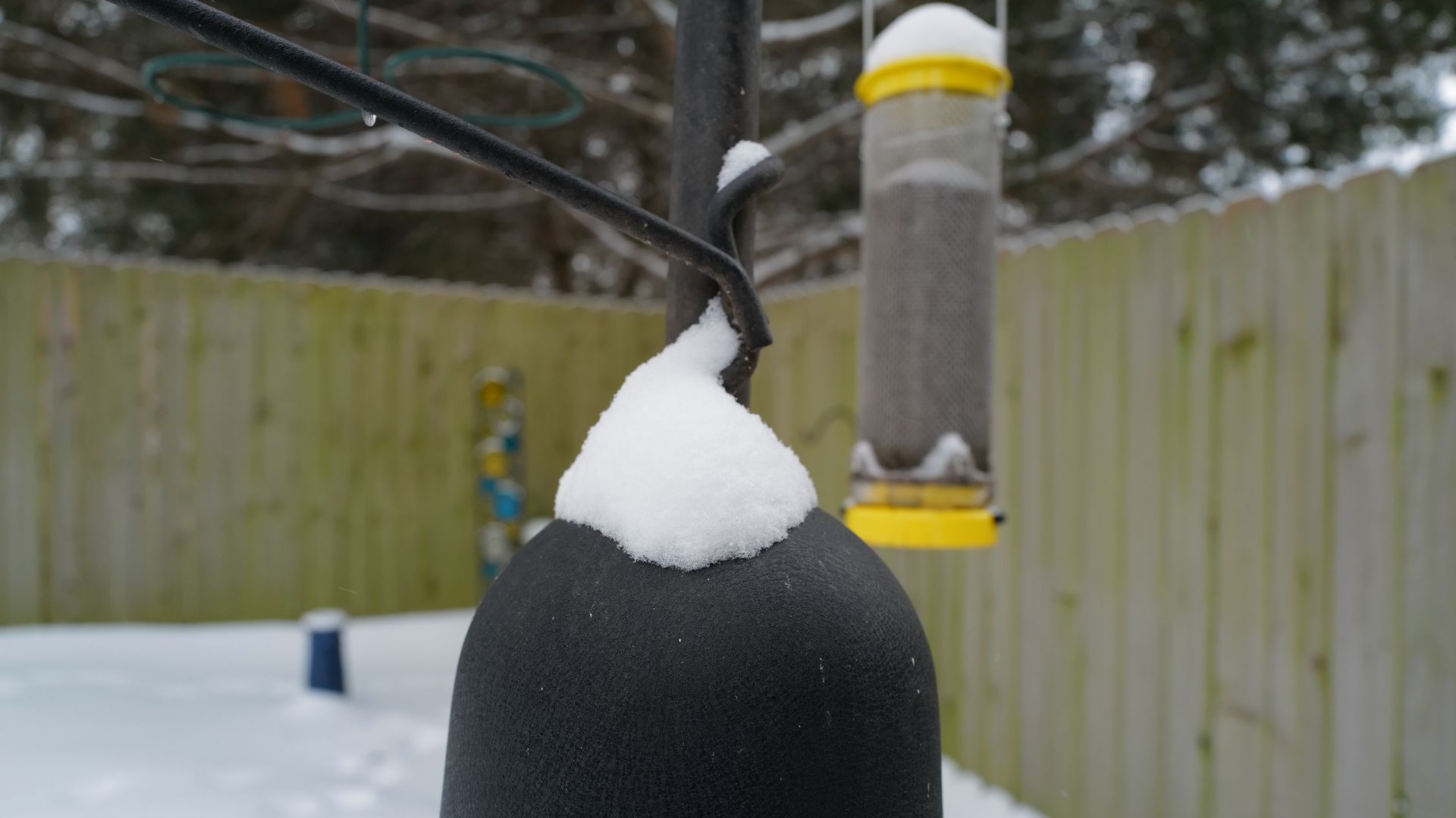 A photo of bird feeders with snow on them. 