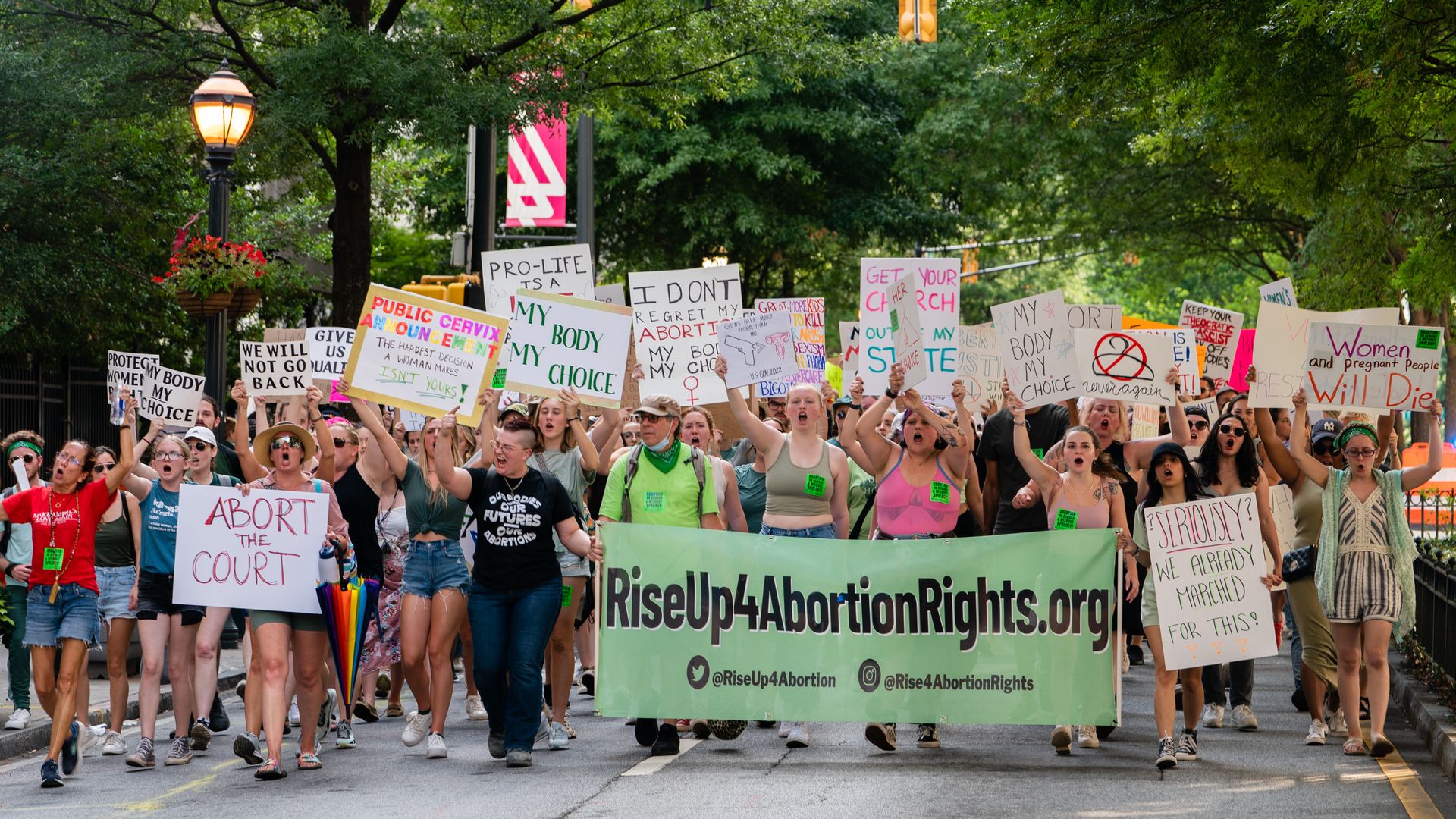 A large group of protesters march in an urban area holding signs advocating for abortion rights 