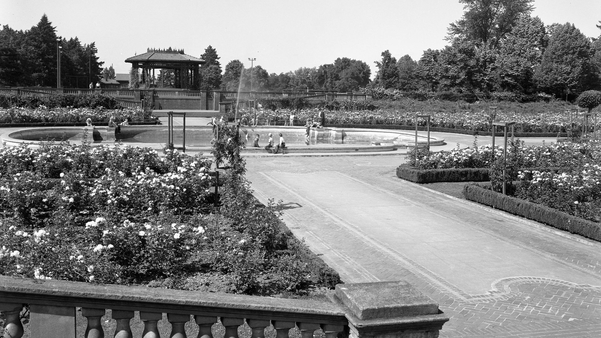 A photo of a fountain with people sitting in front of it.