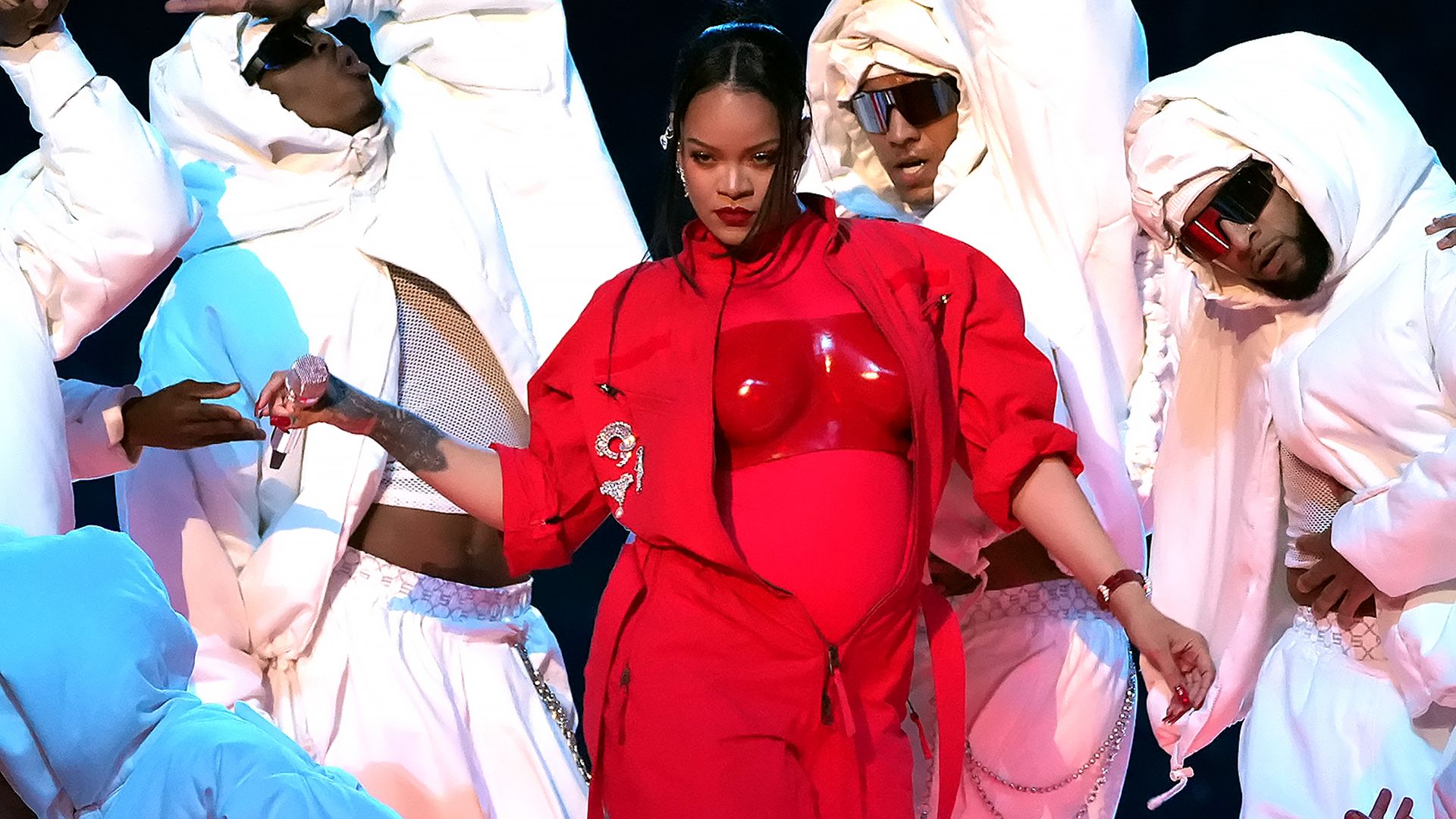woman performer in red attire surrounded by dancers in white