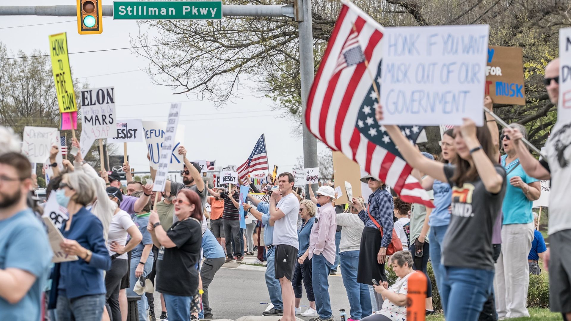dozens and dozens of people holding signs that say i hate elon 