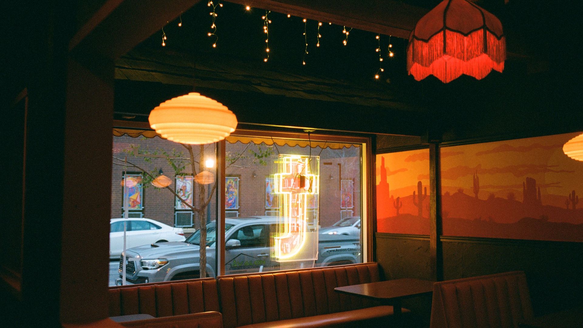 The inside of a restaurant with a neon sign in the shape of the letter T.