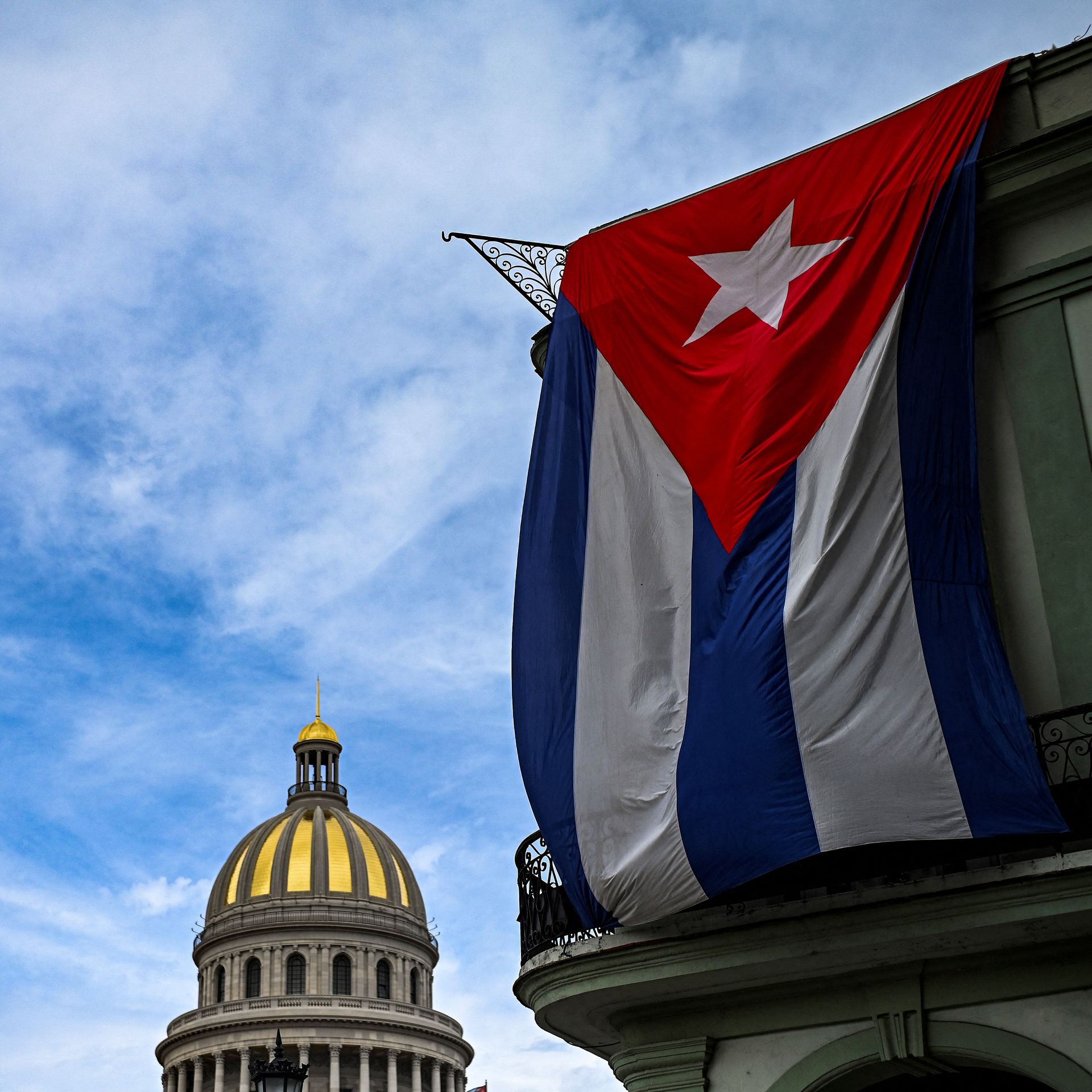 Photo of the Cuban capitol building with a large Cuban flag hanging in the foreground