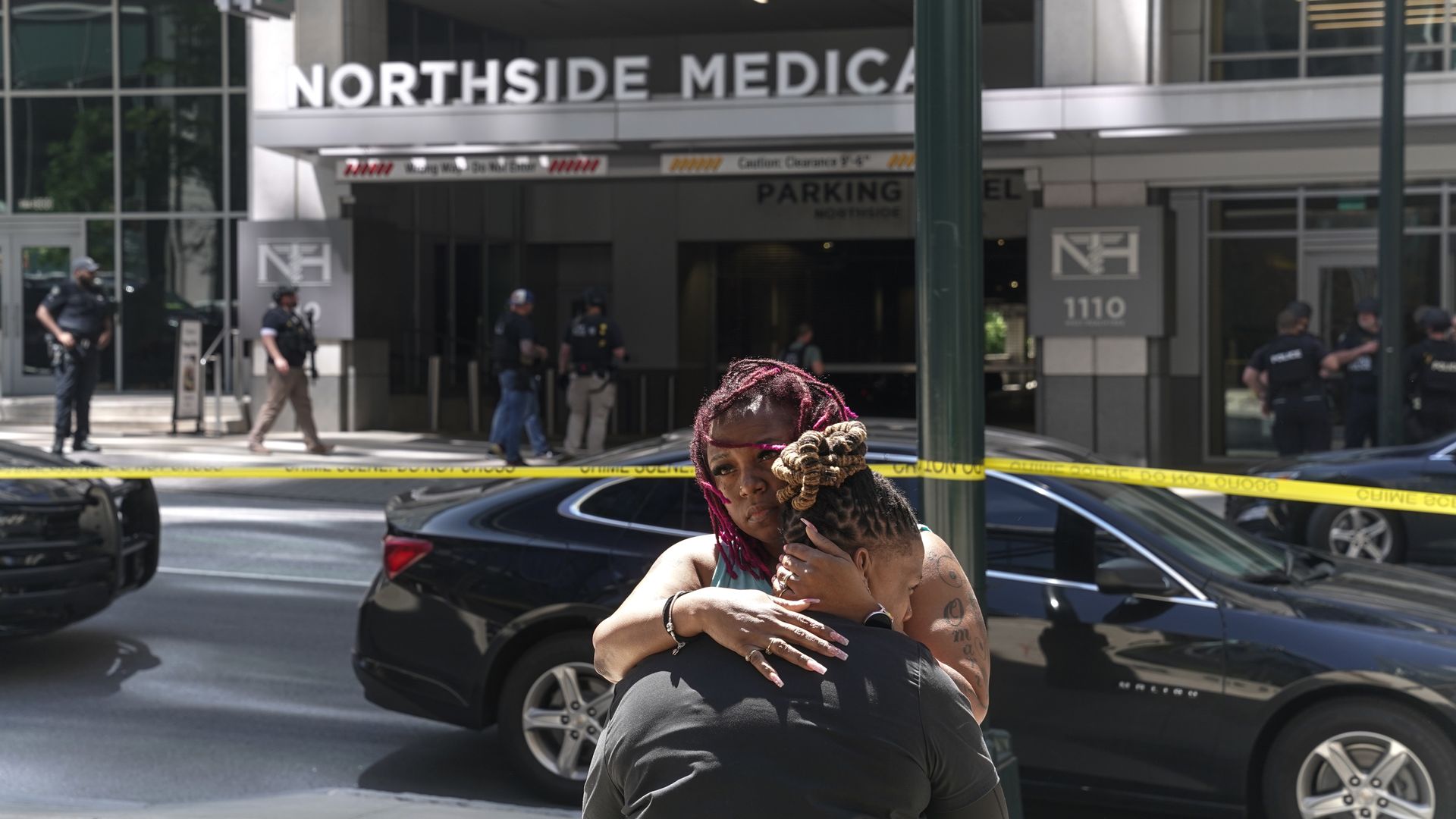 Two women hug outside Northside Medical office building crime scene