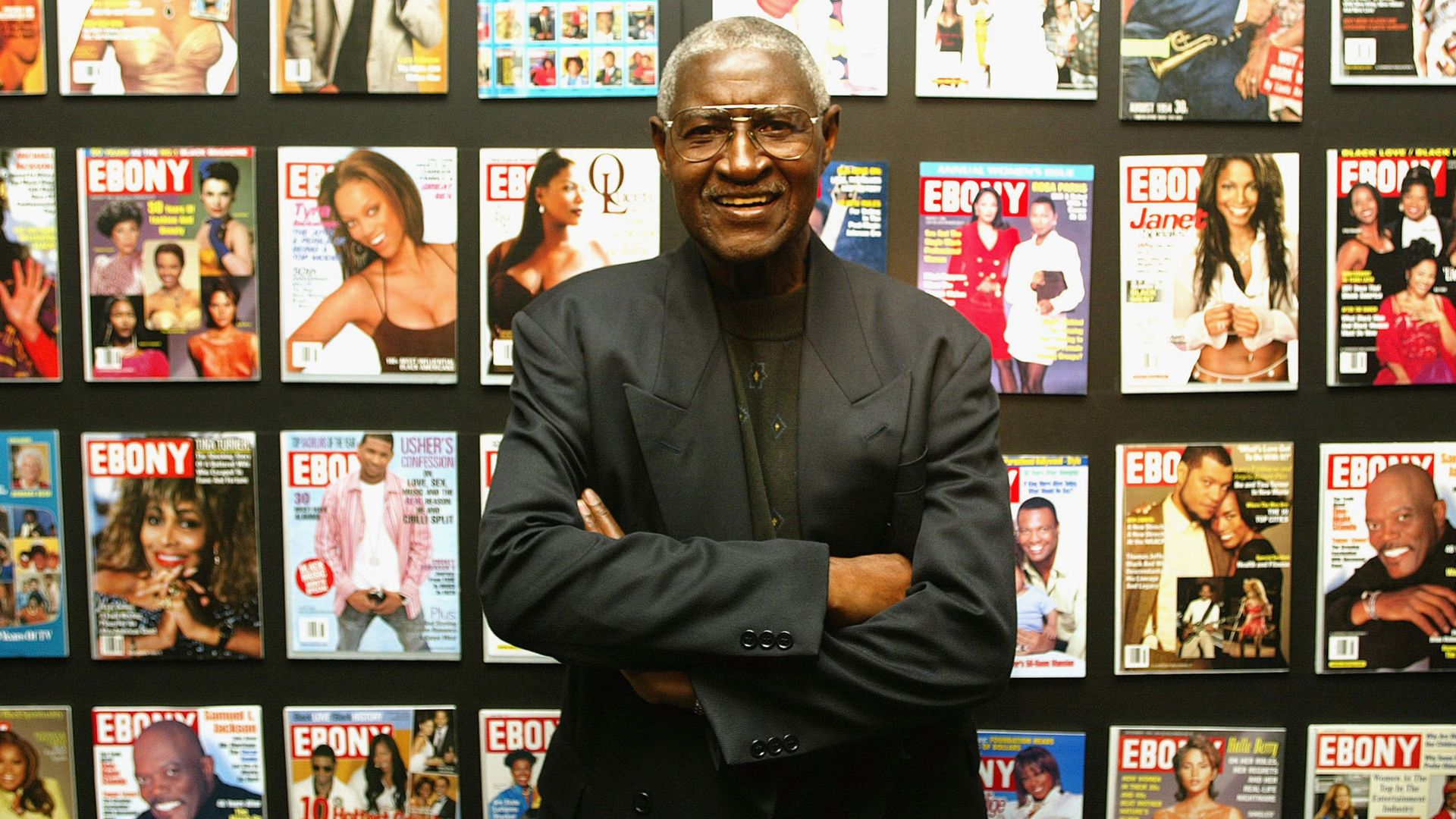 A man posing in front of magazine covers. 