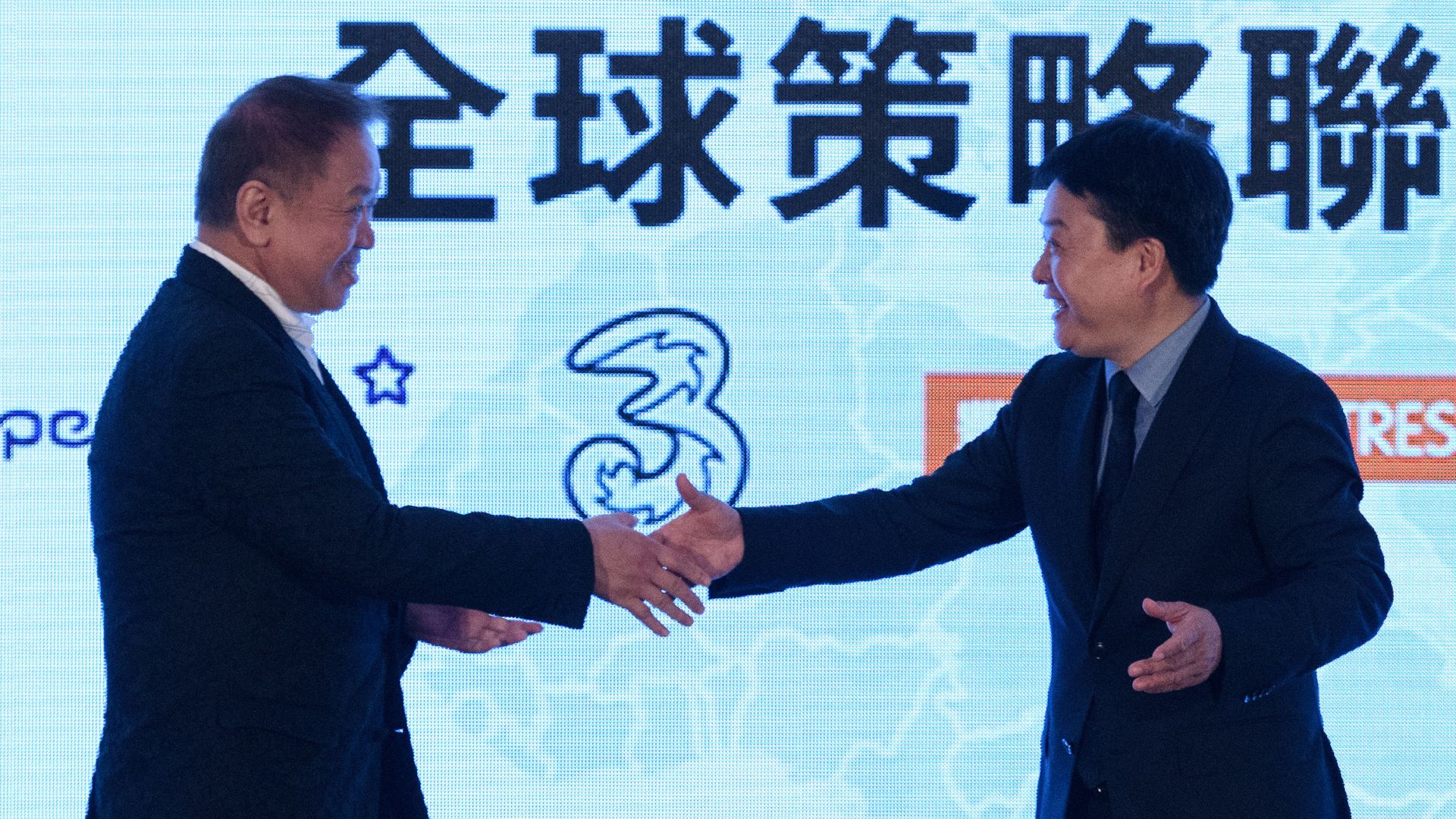 Canning Fok (L), group co-managing director for CK Hutchison (CKHH) and Xiang Wang, senior vice president for Xiaomi, shake hands during a joint press conference