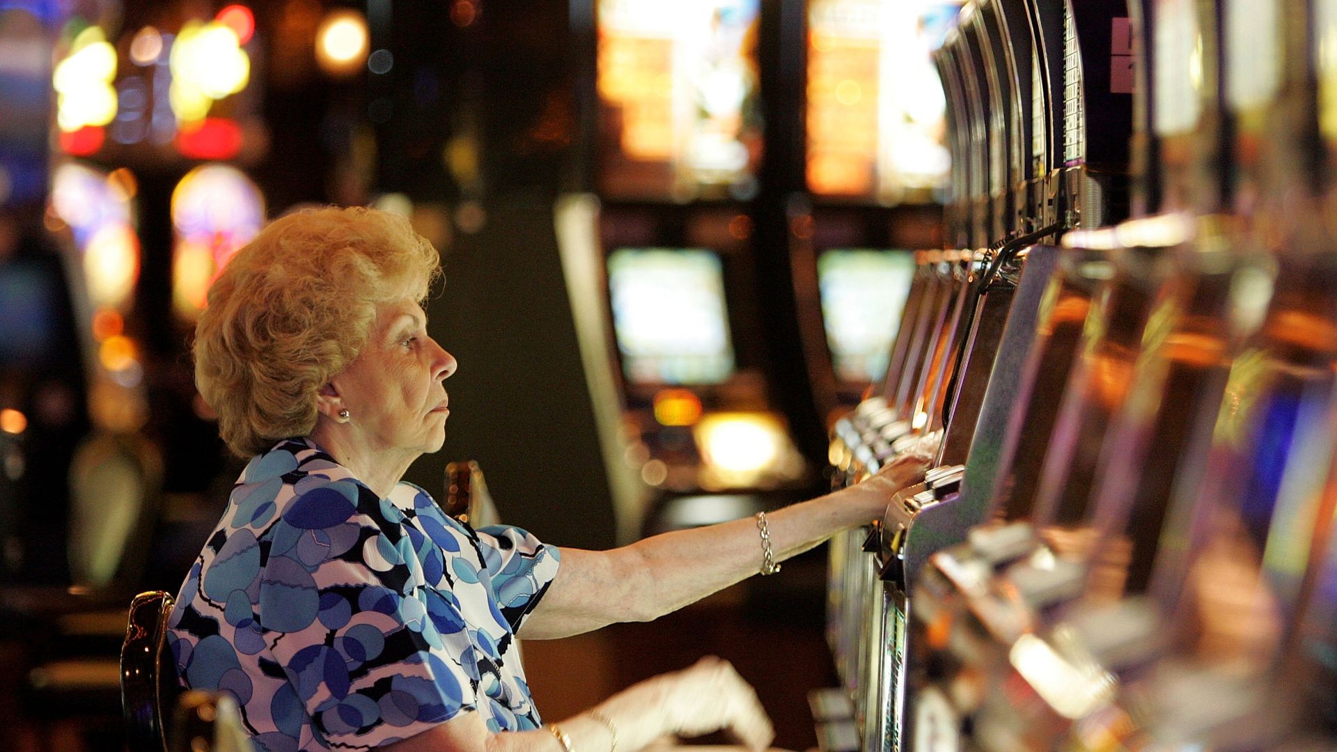 A woman with a serious facial expression plays a slot machine