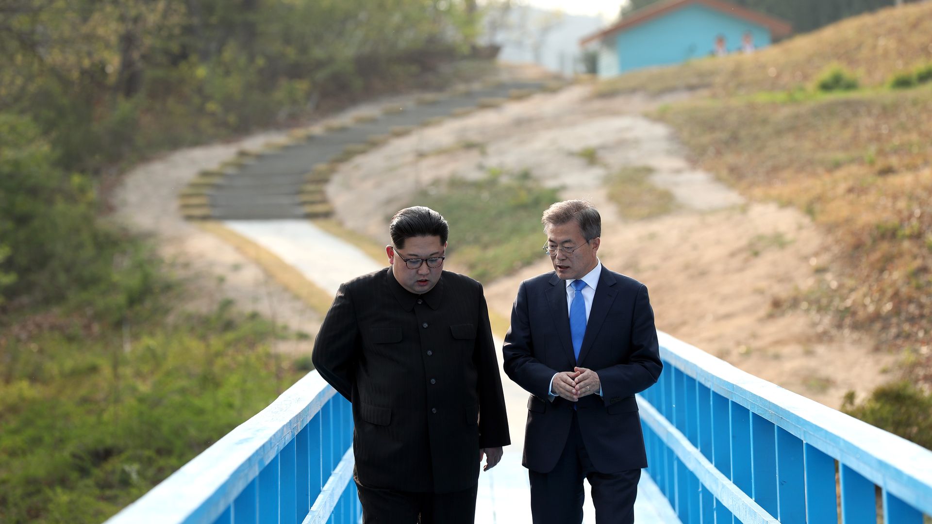 Kim Jong-un and Moon Jae-in walk down a blue bridge.