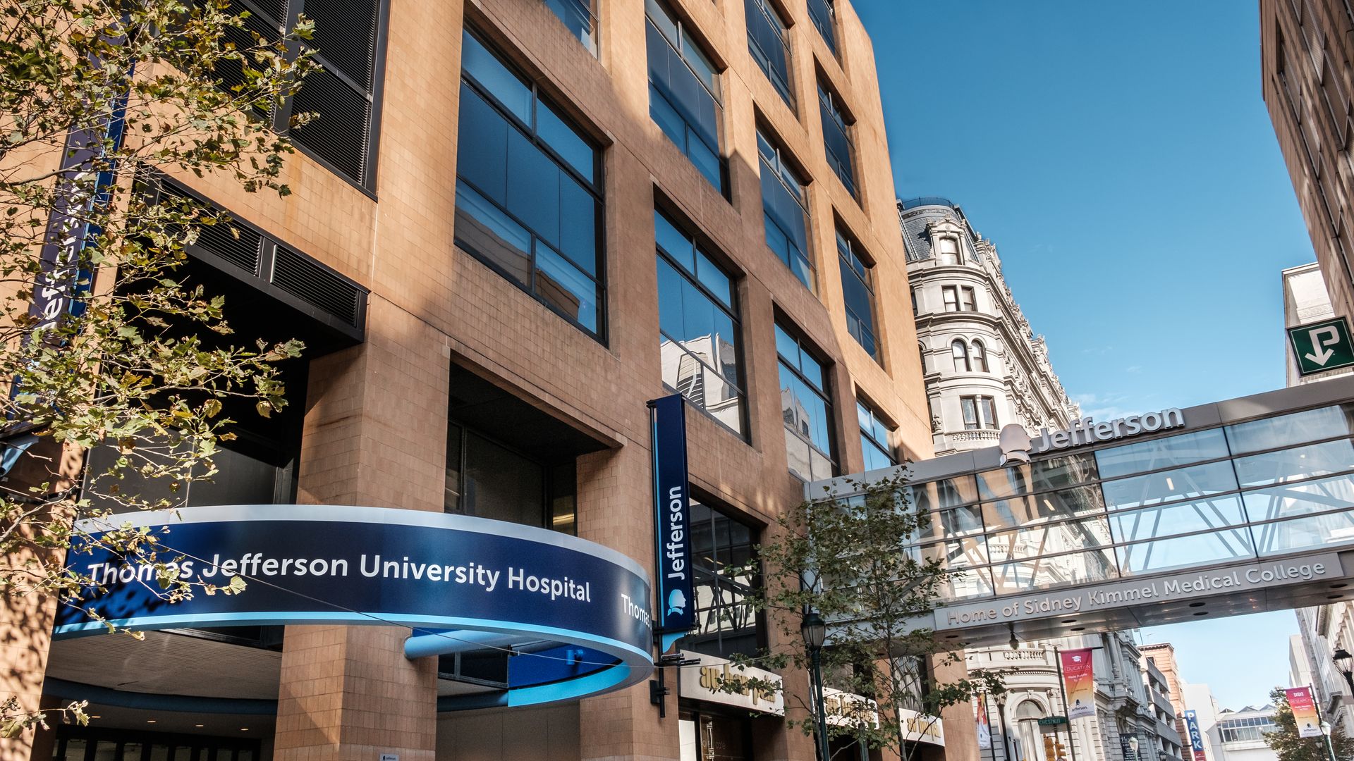 Blue Thomas Jefferson University hospital sign attached to the brown hospital building. 