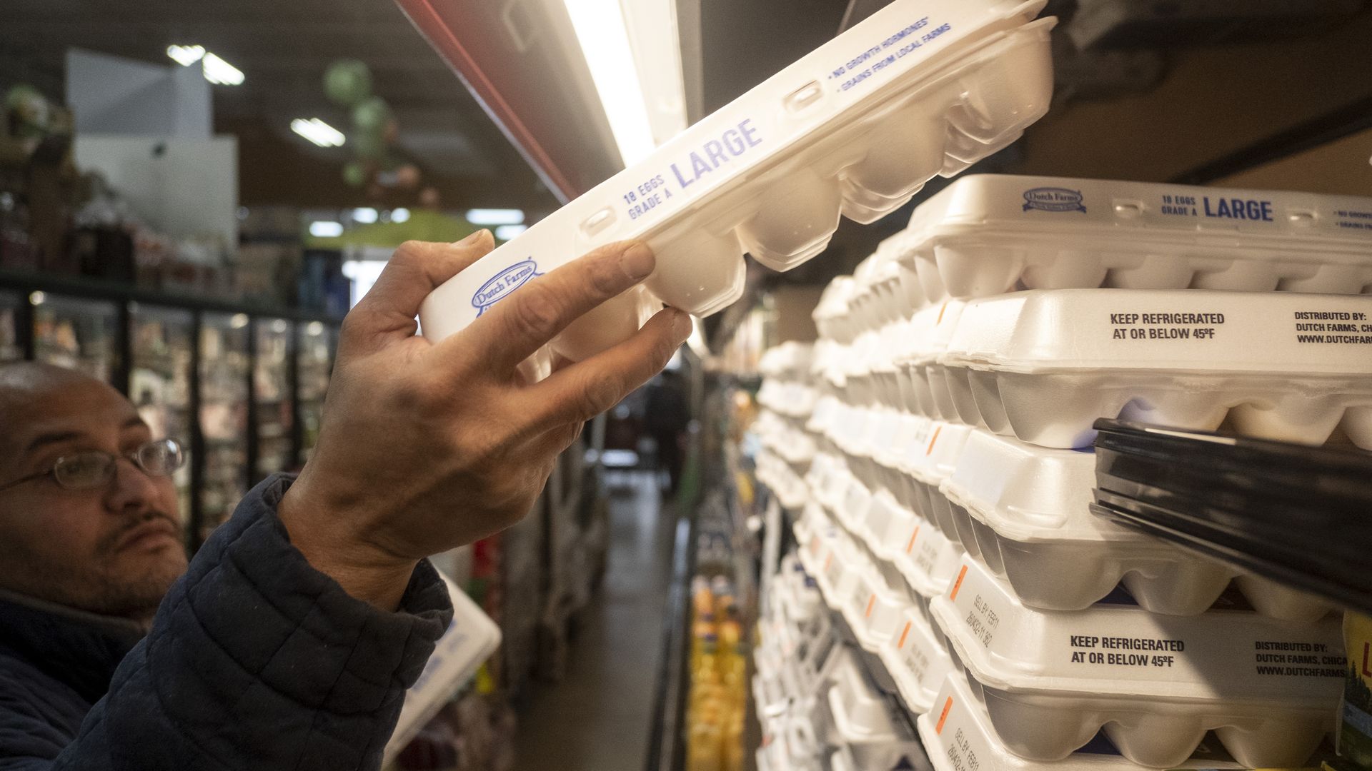 A worker stocks eggs on a grocery shelf