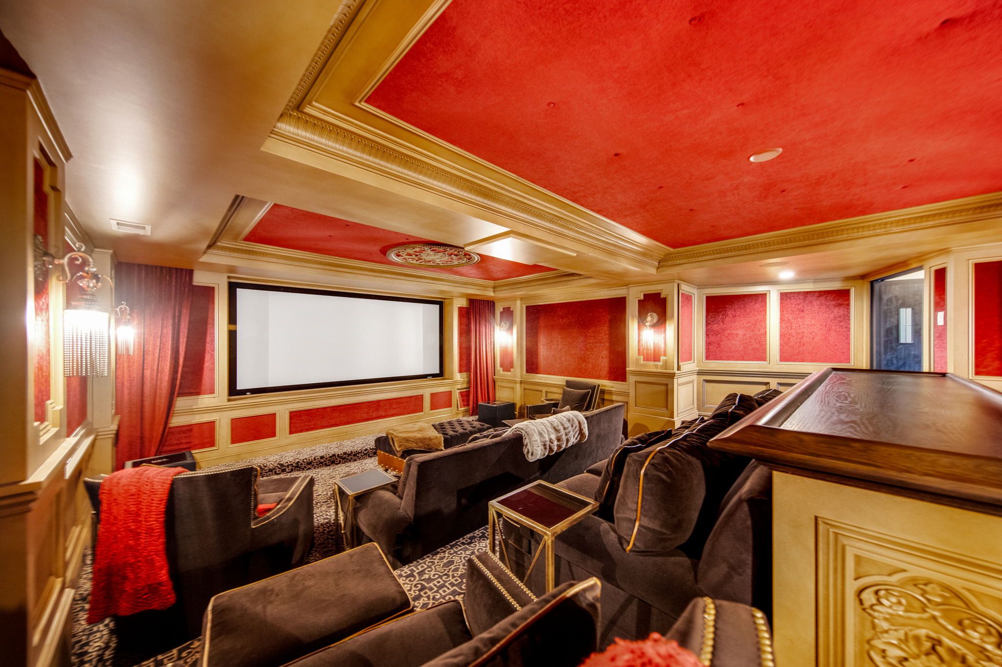 A home theater with red walls and gold accents.