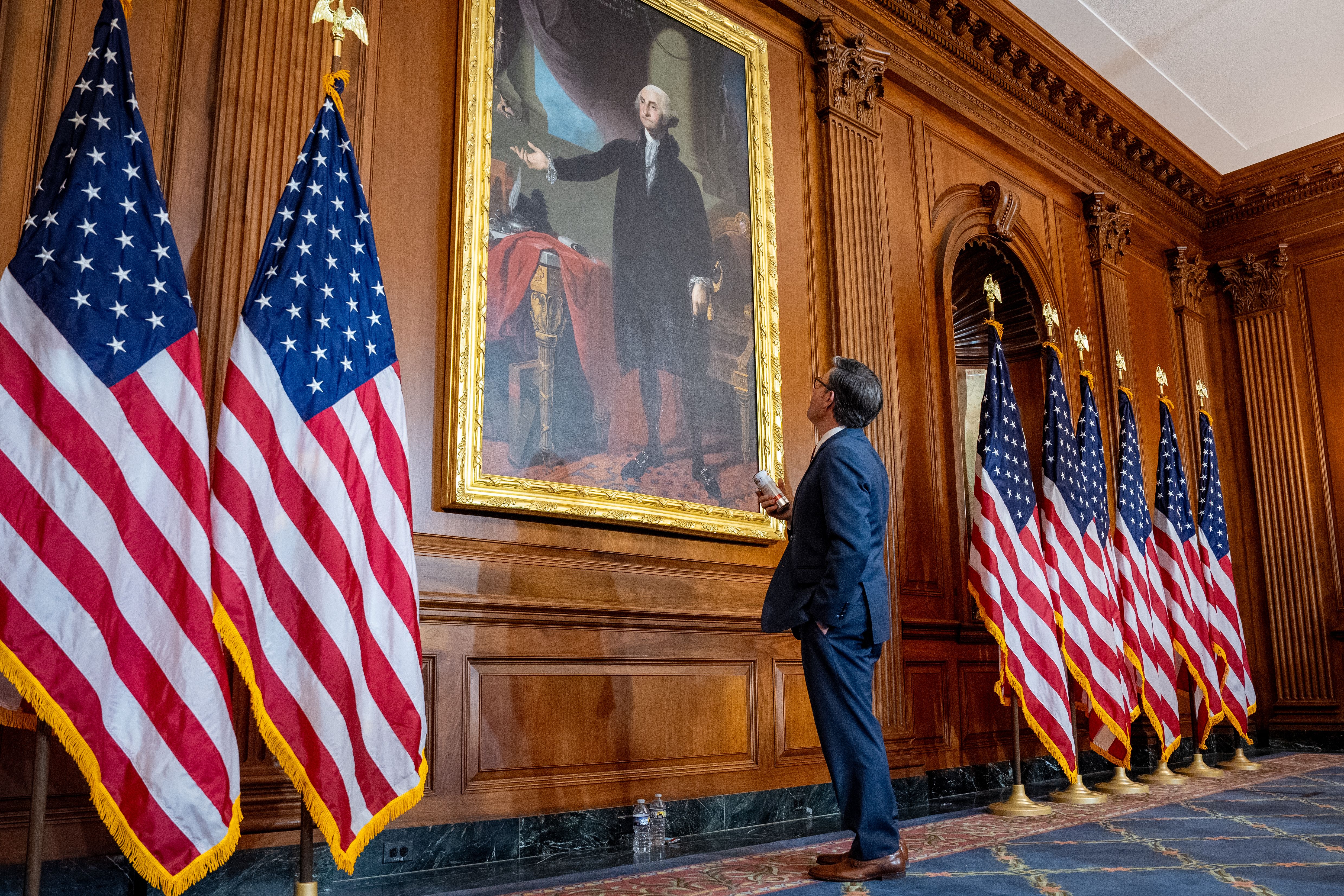 : U.S. Speaker of the House Mike Johnson (R-LA) stops to look at a painting of former U.S. President George Washington while taking a break between ceremonial swearing-in photos with members of Congress after being re-elected Speaker on the first day of the 119th Congress in the U.S. Capitol Buildin