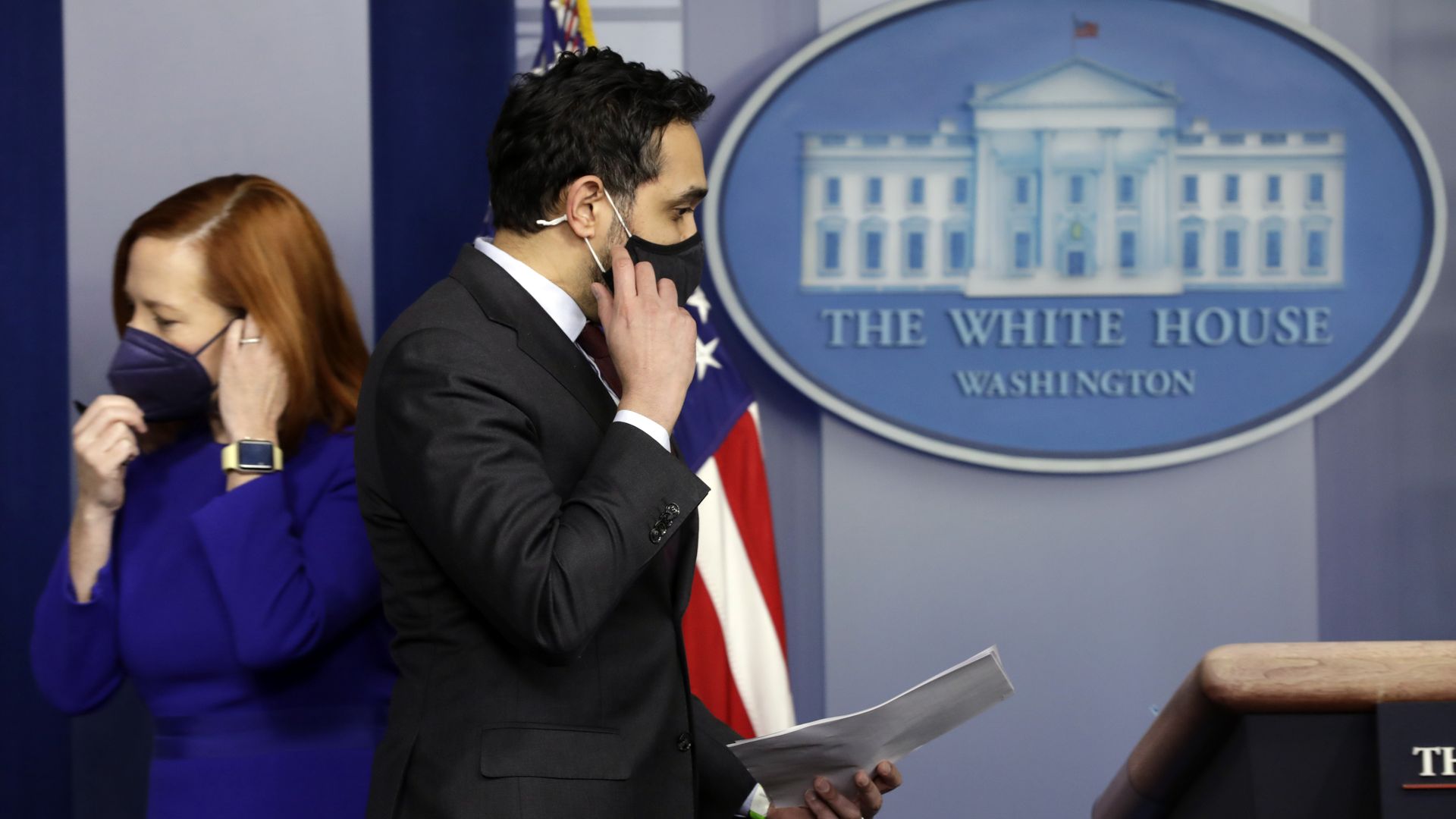 Two White House staffers are seen adjusting their masks while passing in the West Wing.