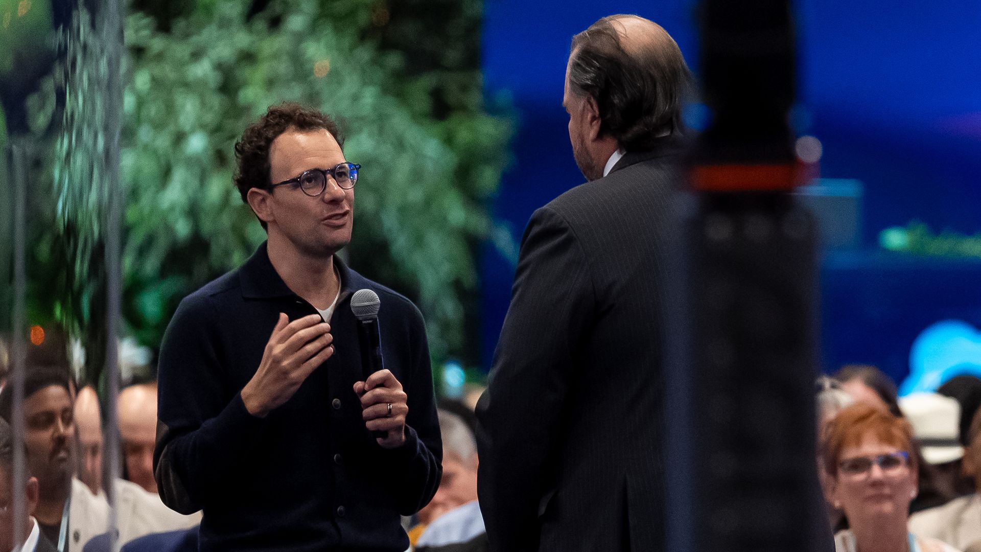 Anthropic CEO Dario Amodei, holding a microphone and speaking to another man.