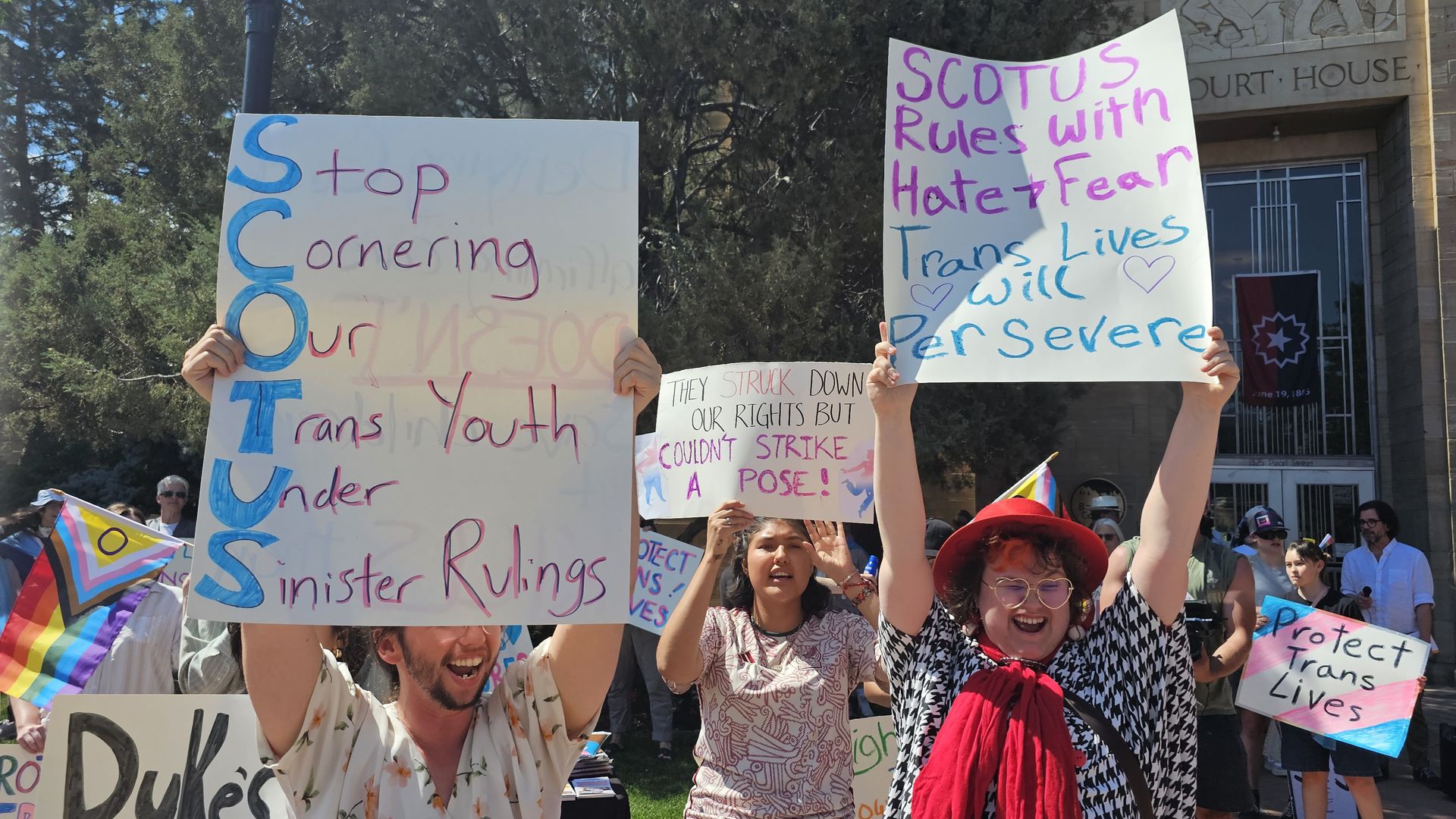 Protesters hold up signs at a Boulder rally for trans rights, including one that says "SCOTUS rules with hate and fear"