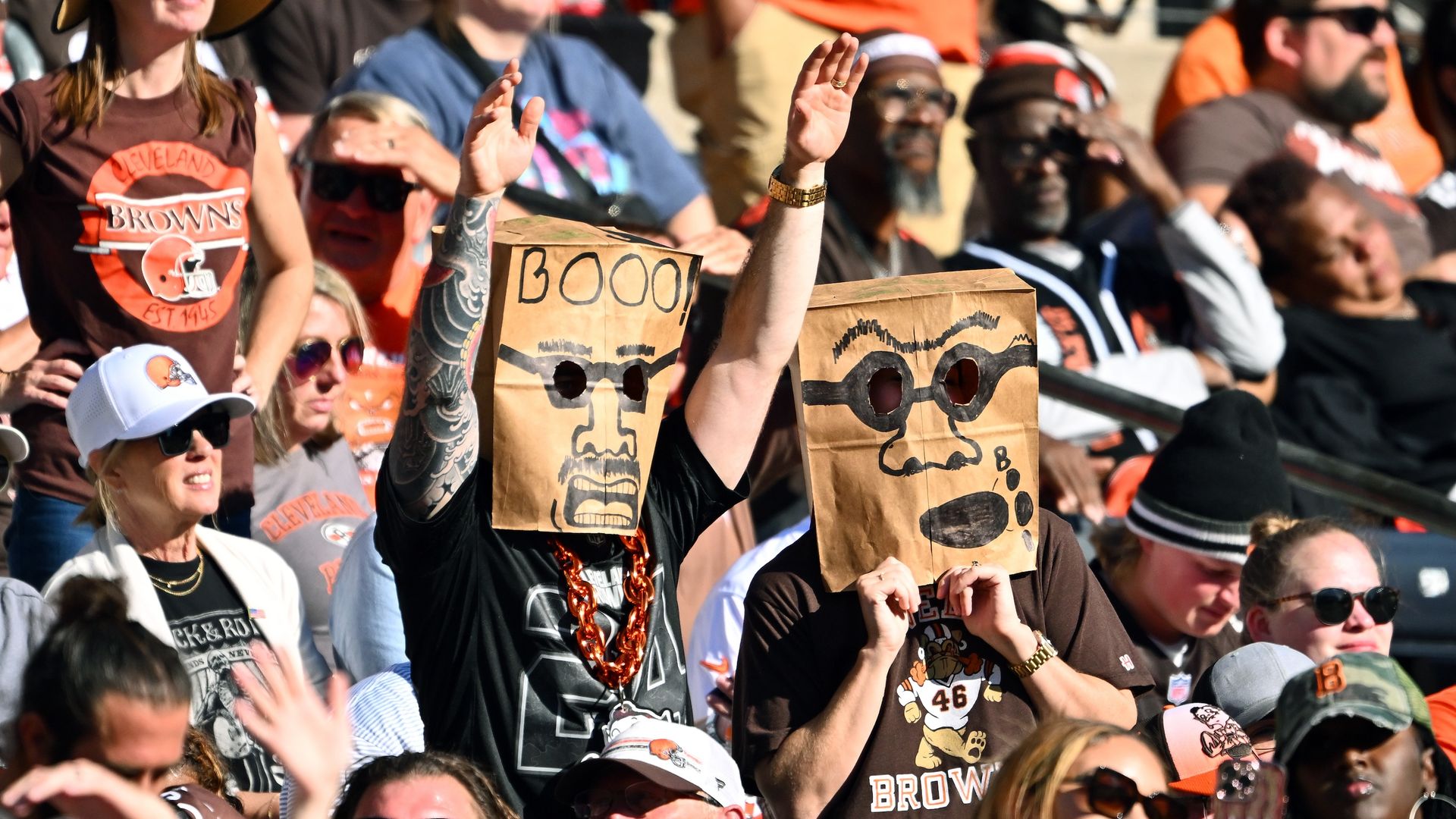 Browns fans at a game where brown bags over their heads. 