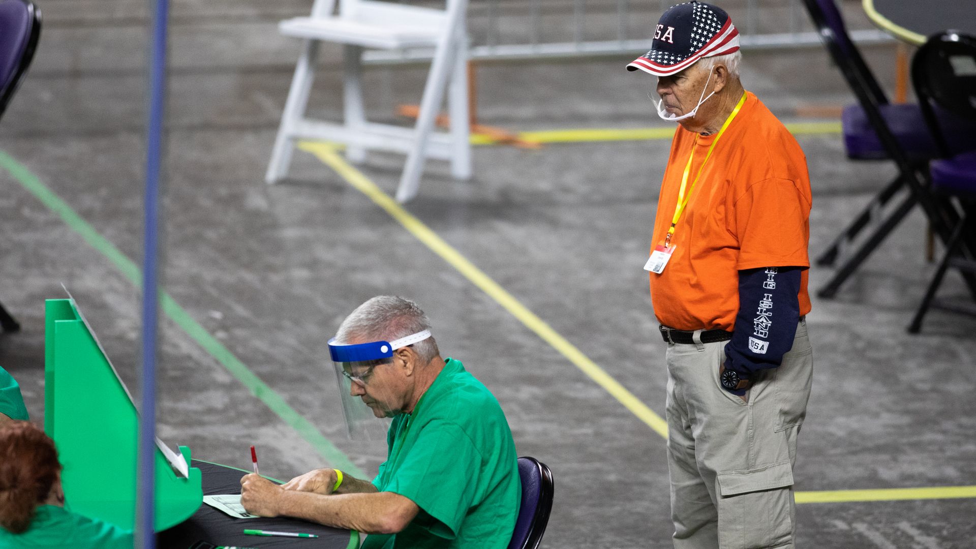 An observer watches as contractors working for Cyber Ninjas, who was hired by the Arizona State Senate, examine and recount ballots from the 2020 general election at Veterans Memorial Coliseum