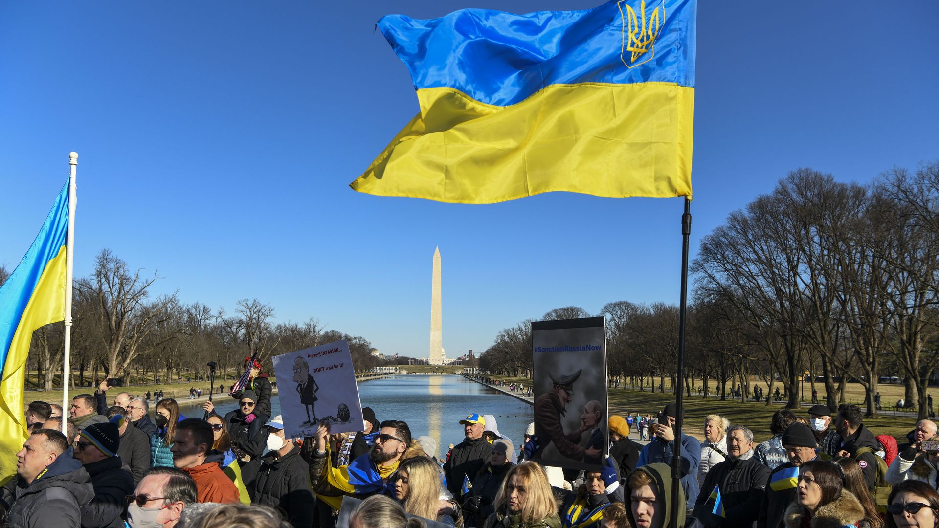 Protesters march with the Washington Monument in the background, calling on President Biden to take a stronger stance on deterring Russia from invading Ukraine.