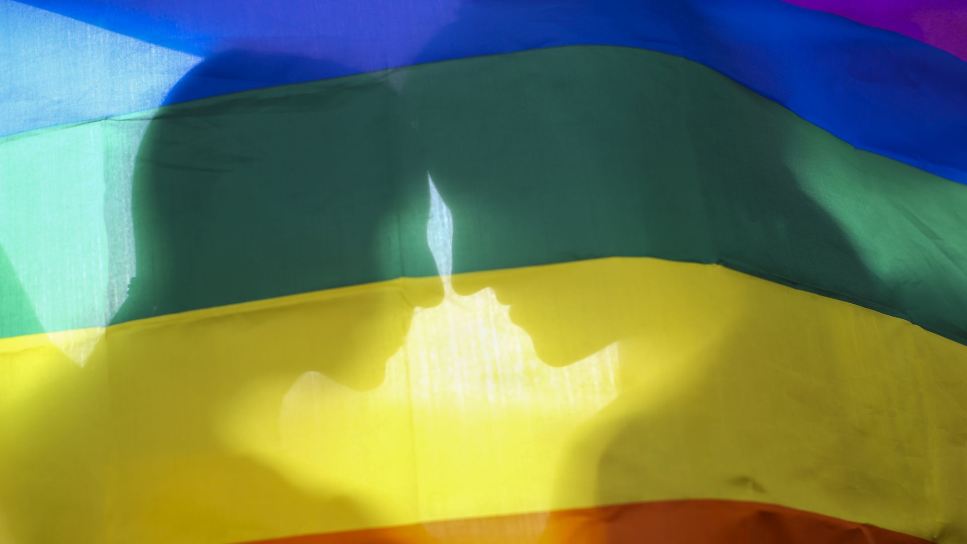 A lesbian couple behind a gay pride flag.