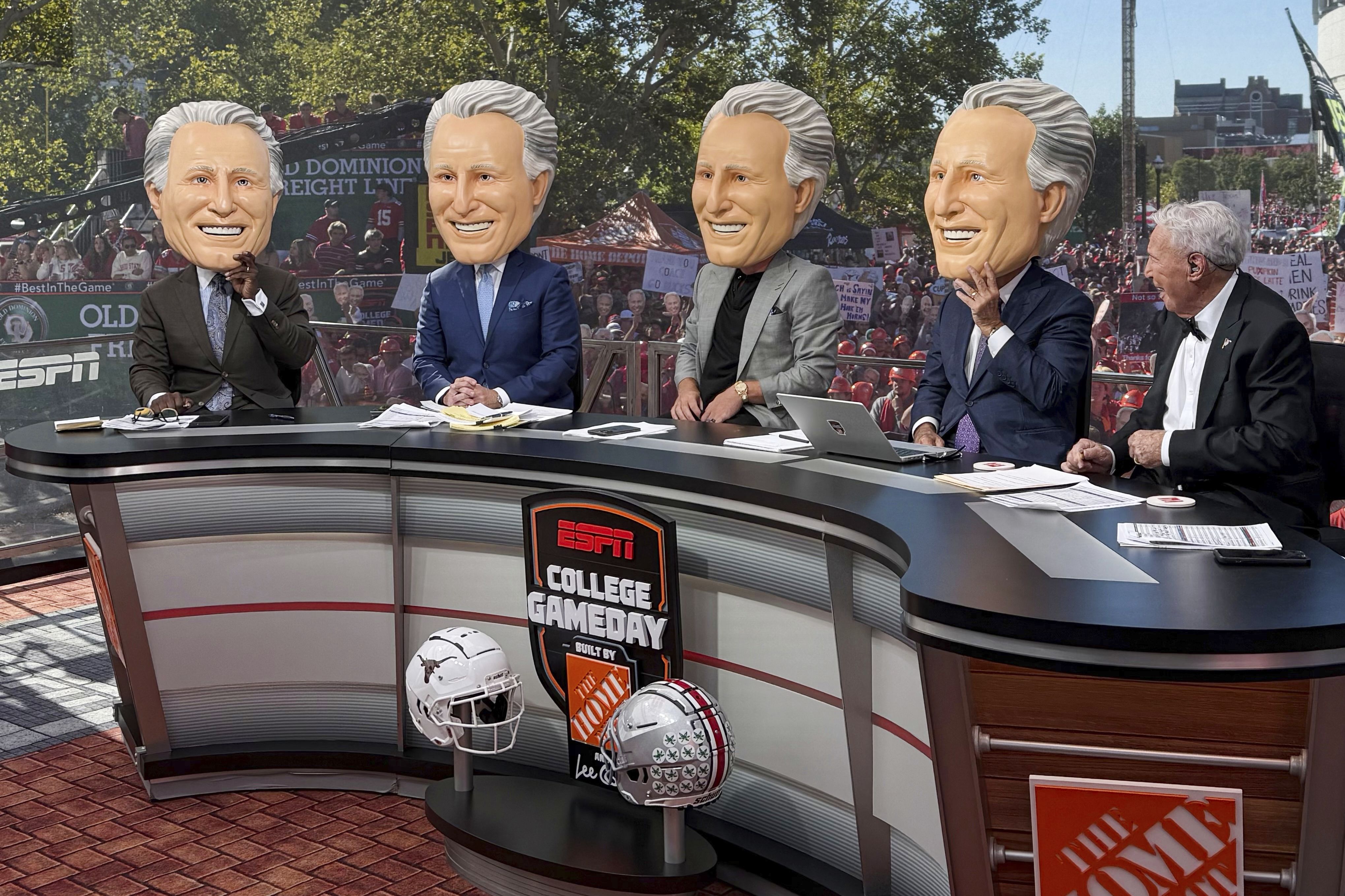 ESPN's Lee Corso, right, reacts as his colleagues don Corso heads during ESPN's "College GameDay," before the NCAA college football game between Ohio State and Texas, Saturday, Aug. 30, 2025, in Columbus, Ohio. (AP Photo/Jospeh Reedy)