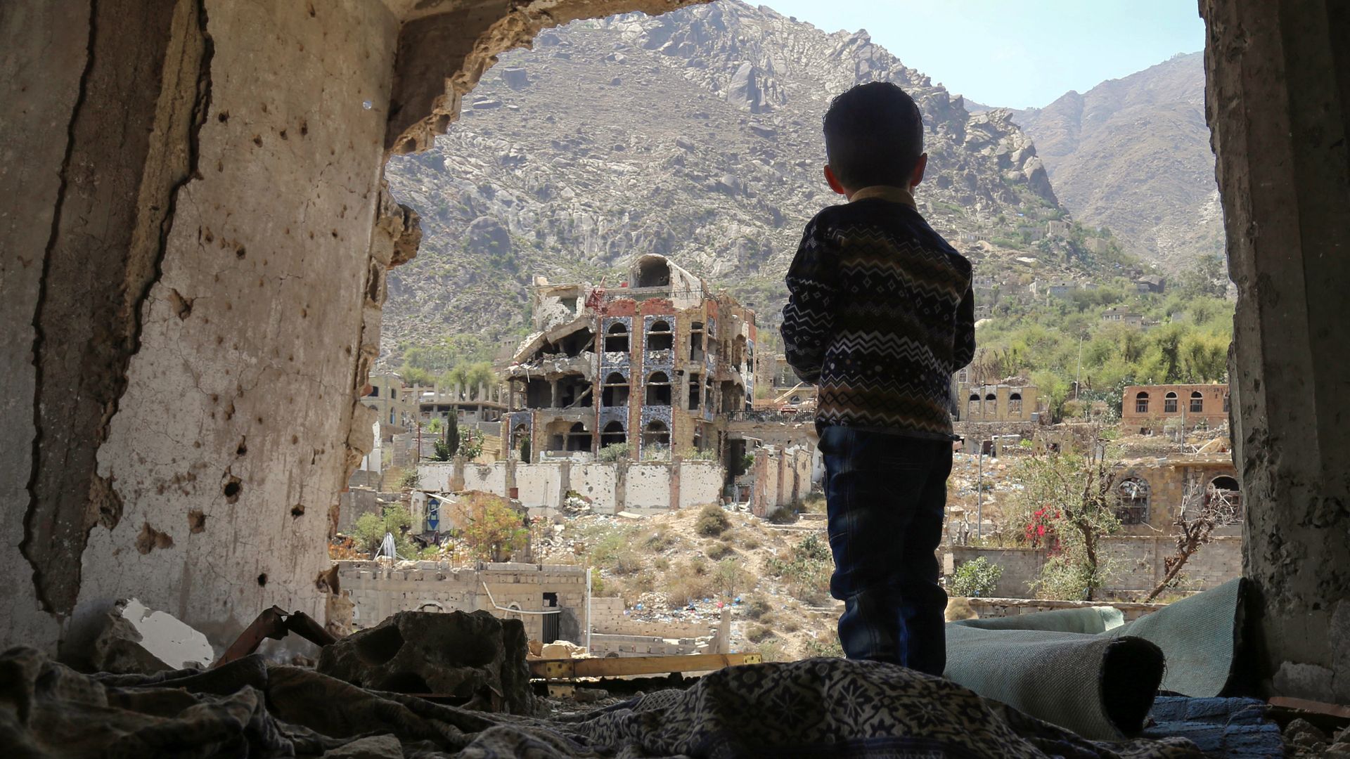 A child in Yemen looking at destroyed buildings.