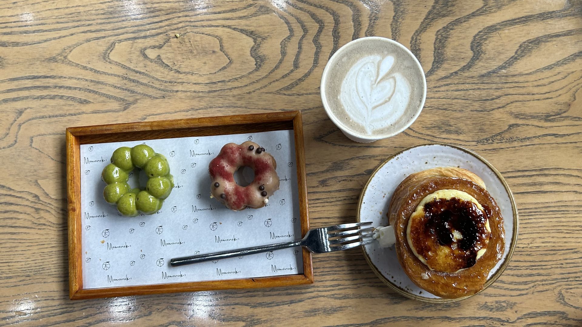A photo of Matcha pastries, a sweet roll, and a latte