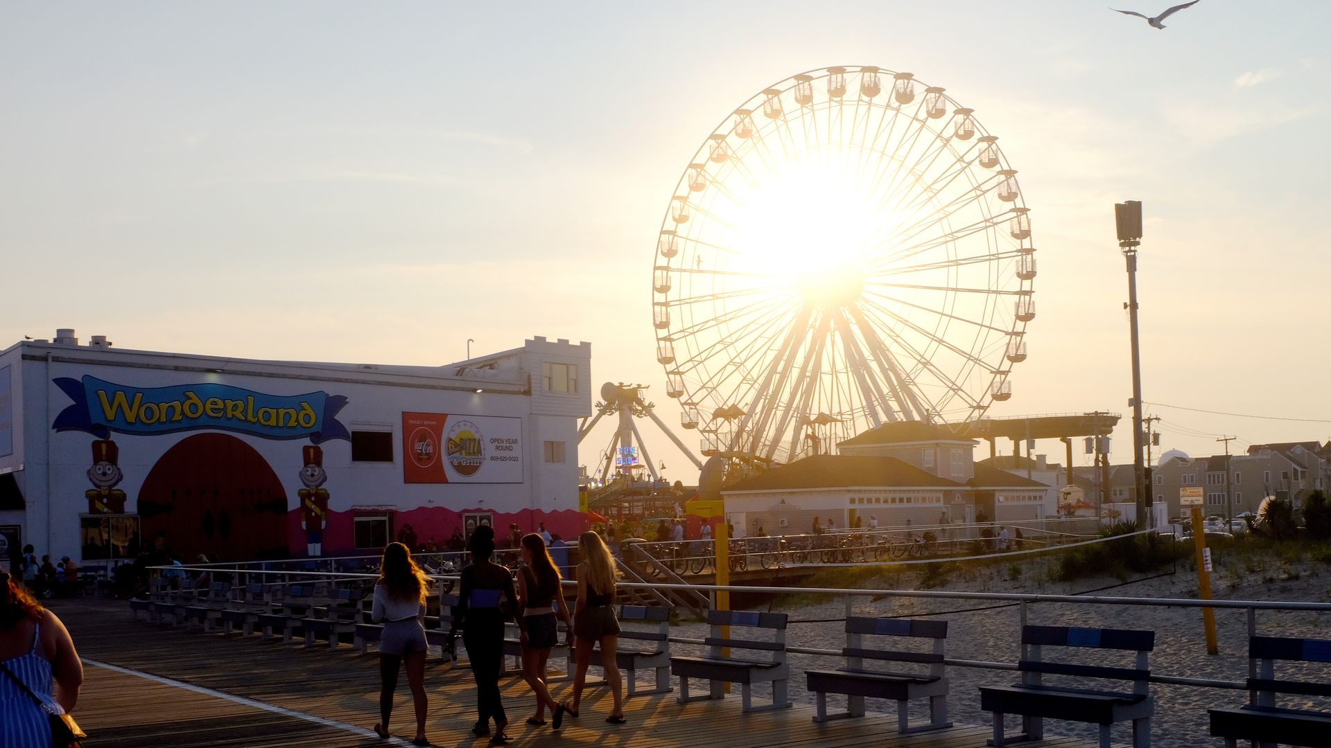 People walk past the ferris wheel of Gillian's Wonderland Pier amusement park on the boardwalk.